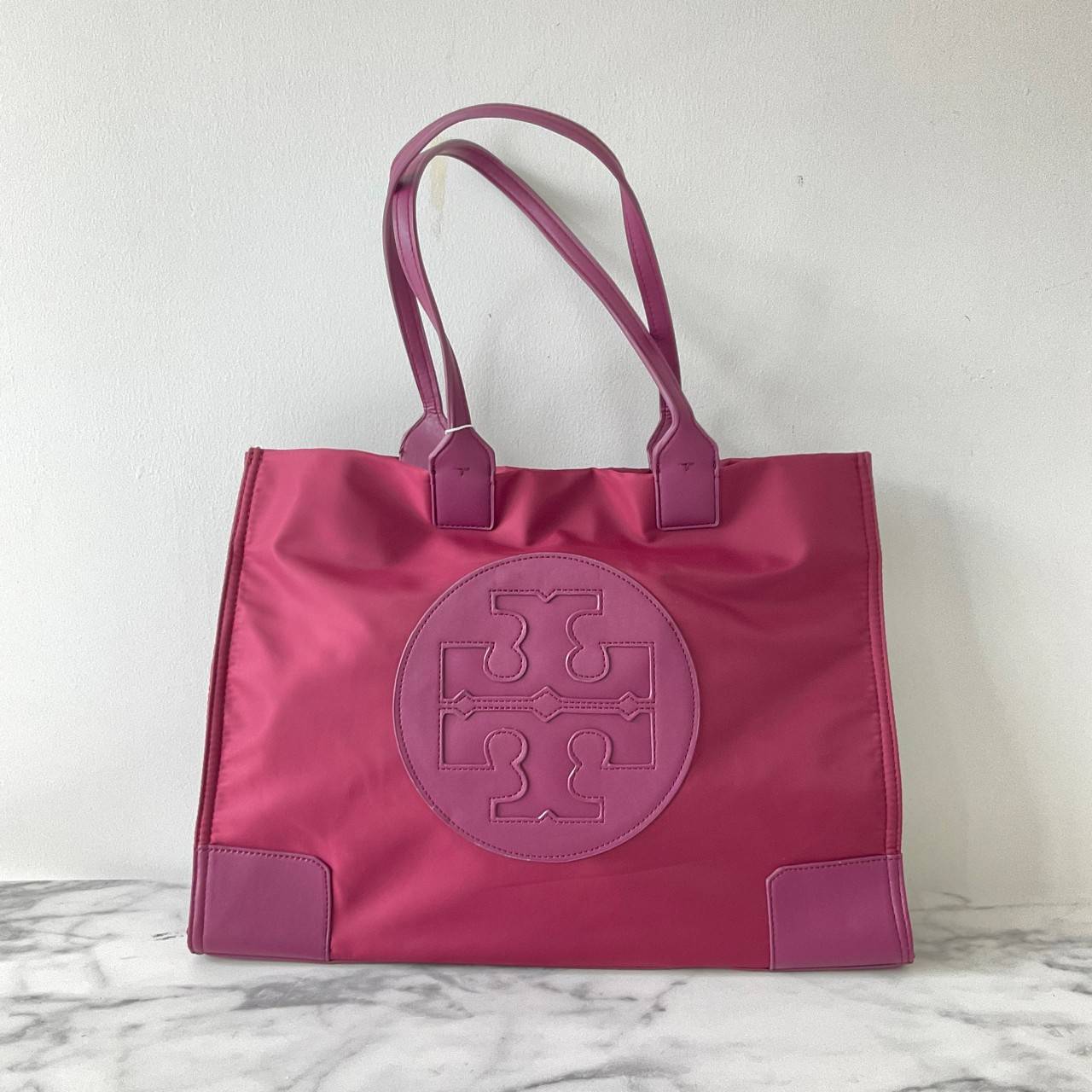 กระเป๋าทรงโท้ทใบใหญ่ TORY BURCH ELLA TOTE BAG วัสดุ NYLON ทั้งใบตัดด้วยหนังสีดำ แต่งโลโก้แบรนด์ด้านหน้า ด้านข้างมีกระดุม สามารถขยายทรงได้ ด้านในเปิดปิดด้วยกระดุมแม่เหล็กฝัง ช่องกว้างหลักหนึ่งช่องและช่องซิปอีกช่อง สามารถใส่แล็ปท็อปได้สบาย ใบใหญ่เว่อวัง ไอเ