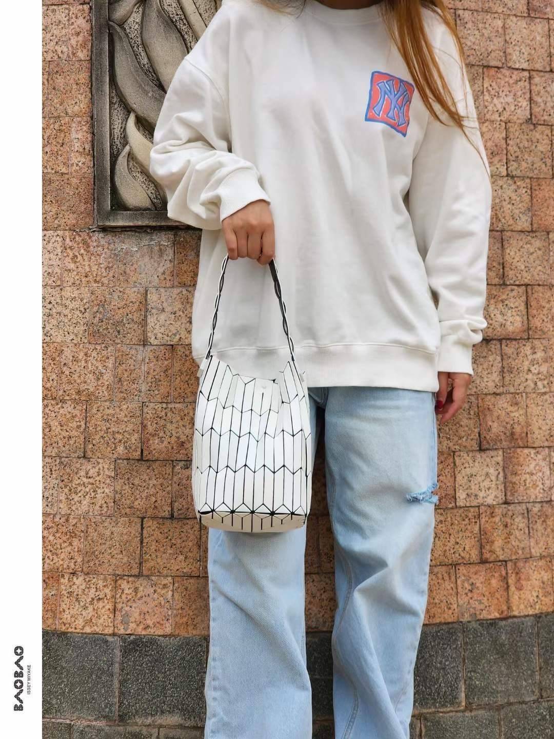 Small : BAO BAO ISSEY MIYAKE SMALL BUCKET เป็นกระเป๋าบัคเก็ตขนาดเล็กสามารถใช้ใส่กระเป๋าสตางค์และโทรศัพท์มือถือได้ ซีรีย์ใหม่นี้มีจุดเด่นที่แผ่นรูปทรงสี่เหลี่ยมด้านขนานในแนวตั้ง เกิดเป็นรูปทรงสามมิติซึ่งแตกต่างไปจากรูปทรงที่เกิดขึ้นจากแผ่นสามเหลี่ยม หูหิ้ว