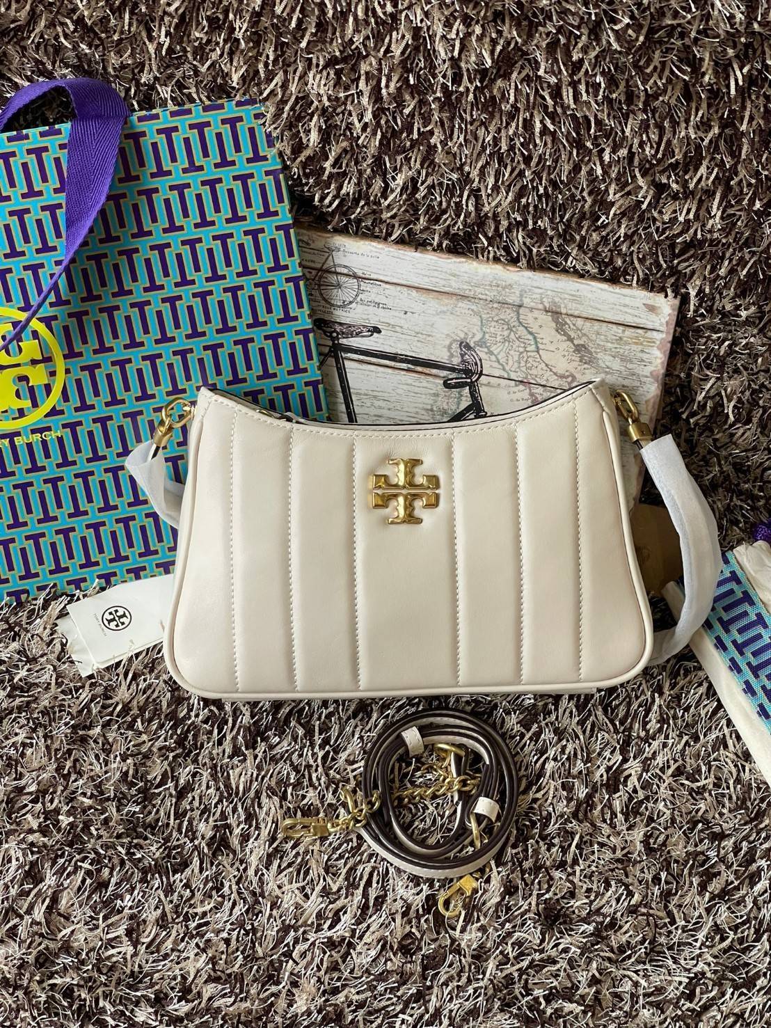 Tory burch Kira logo-plaque crossbody bag กระเป๋า Kira ของ Tory Burch เป็นส่วนหนึ่งของคอลเล็กชั่นที่โดดเด่น และมีหลายรุ่นด้วยกัน โดยมีป้ายโลโก้ Double T ของแบรนด์อยู่ตรงกลาง มีความเรียบง่ายแต่ยังคงความหรูหราโดดเด่นด้วยวัสดุบุผิว ป้ายโลโก้สีทอง สายสะพายโซ่