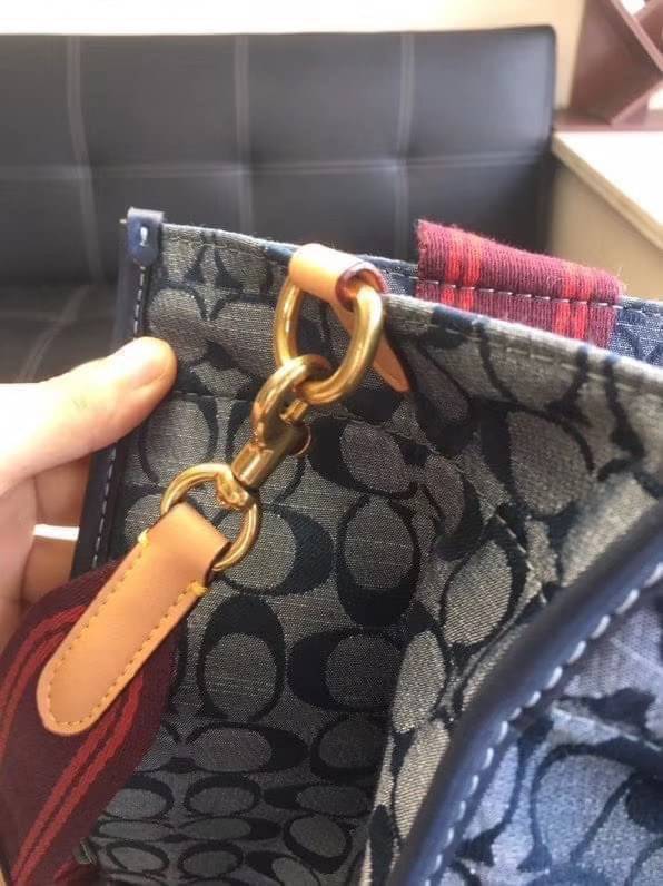 COACH Tote 34 In Signature Chambray หากคุณกำลังมองหากระเป๋าที่มีดีไซน์แปลกตา ไม่ค่อยเหมือนที่พบเห็นทั่วไป ต้องเป็นรุ่นนี้เลยค่ะ นอกจากจะผลิตจากผ้าแชมเบรย์ซึ่งมีน้ำหนักเบาแล้ว ยังให้สีสันคล้ายกับสียีนส์ สายสะพายและหูหิ้วสไตล์สปอร์ต ที่สำคัญยังมีหมุดปิดกระเ