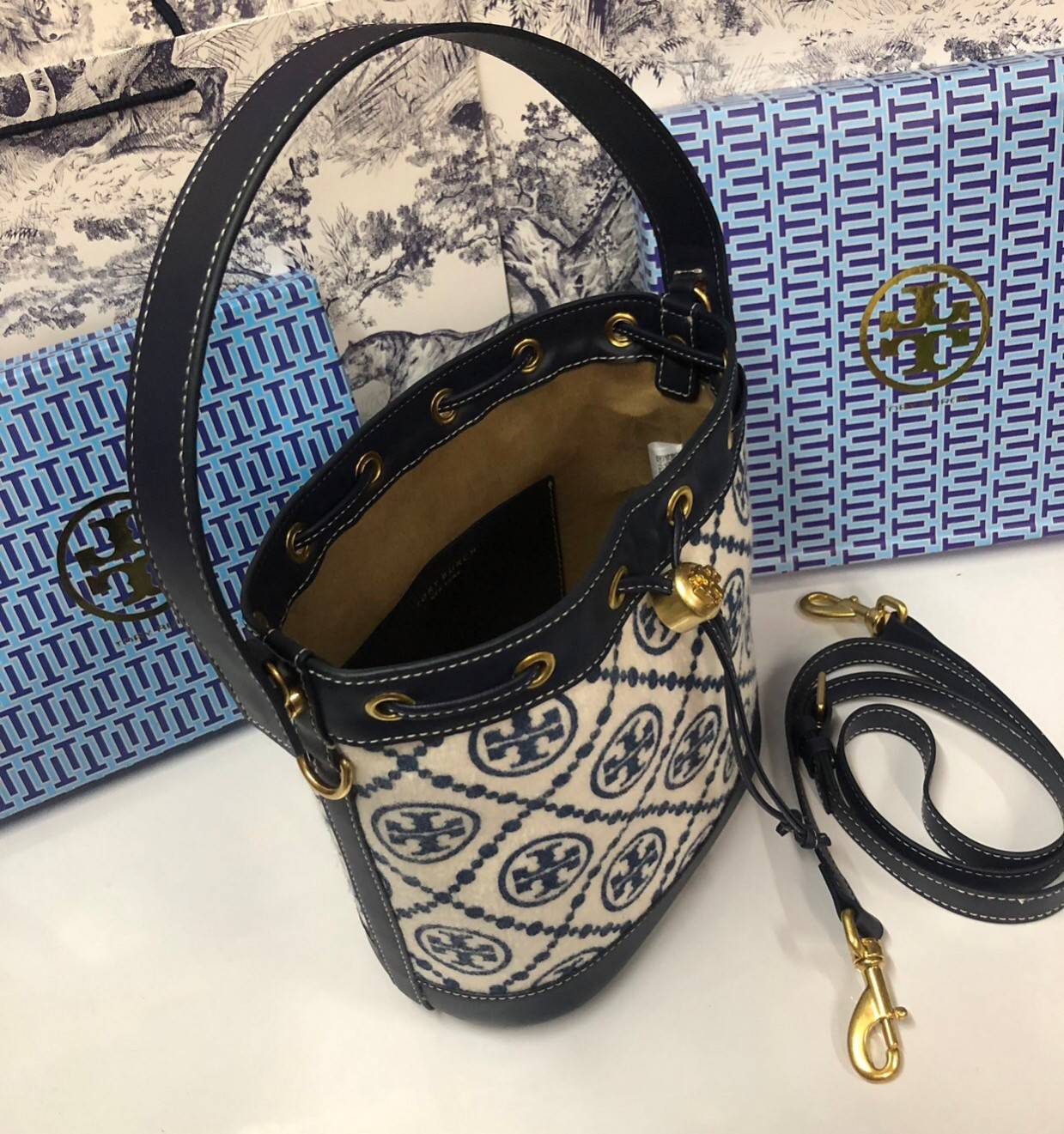 Medium : Tory Burch T Monogram Chenille Bucket Bag เปิดตัวอีกหนึ่งรุ่นกับกระเป๋าลาย T MONOGRAM รุ่นใหม่ล่าสุดจาก TORY BURCH พลาดไม่ได้กับโลโก้สุดคลาสสิก ลวดลาย T Monogram คือวัสดุ chenille หรือที่เรียกว่า ด้านไหมกำมะหยี่ มารังสรรค์ลงบนกระเป๋าBucketใบนี้ เ