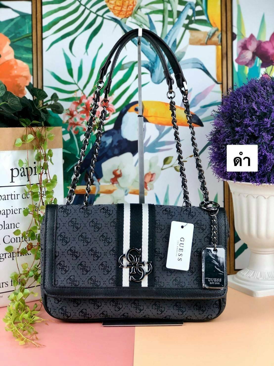 Guess Logo city handbag กระเป๋าสะพายไหล่ ตัวกระเป๋าเป็นผ้าลาย signature ของแบรนด์ ตัดกับหนังที่ตัวขอบกระเป๋า มาพร้อมพวงกุญแจโลโก้แบรนด์ ด้านหน้ามีโลโก้แบรนด์ ด้านหลังมีช่องใส่โทรศัพท์/บัตรได้ เปิดปิดแบบกระดุมแม่เหล็กซ้าย-ขวา ด้านในมีช่องซิป เล็ก 1 ช่อง แล