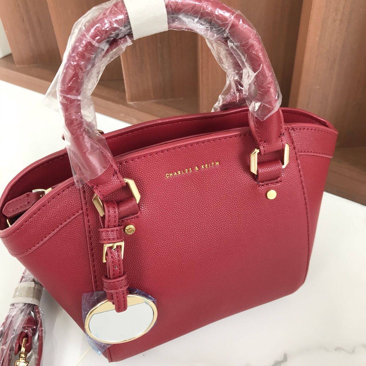 CHARLES & KEITH CITY BAG กระเป๋าถือหรือสะพาย ตั้งอยู่ทรงสวย มีโลหะรองฐาน เปิดปิดด้วยซิปเดียว ภายในมี 2 ช่องเล็กด้านหน้าประดับด้วยกระจกทรงกลม ใช้งานได้จริง ปั้มโลโก้แบรนด์ มาพร้อมสายสะพายยาว ปรับระดับและถอดสายได้ หูพับลงได้ น้ำหนักเบา ต้องมีไว้ครอบครองสักใ