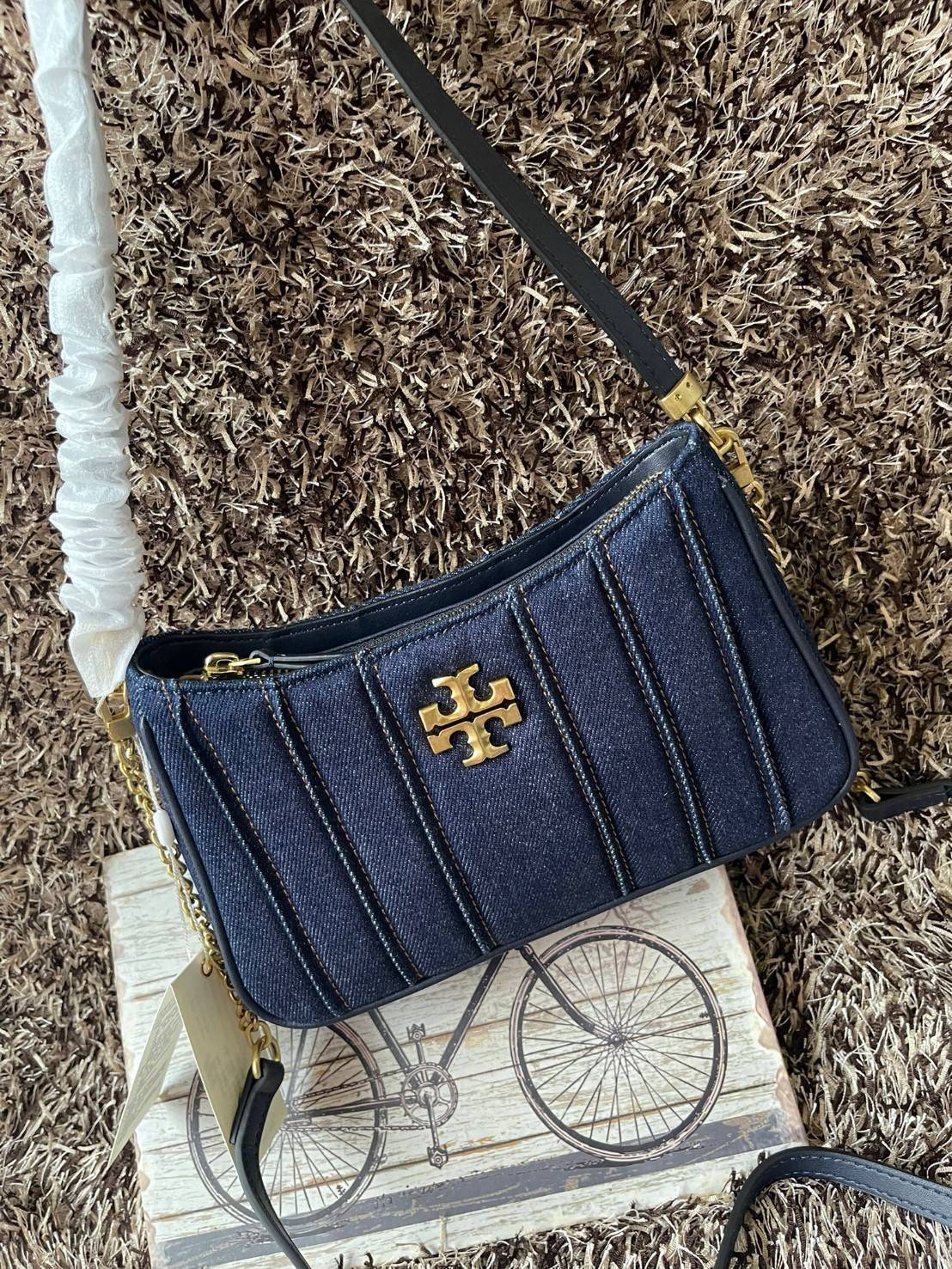 Tory burch Kira logo-plaque crossbody bag กระเป๋า Kira ของ Tory Burch เป็นส่วนหนึ่งของคอลเล็กชั่นที่โดดเด่น และมีหลายรุ่นด้วยกัน โดยมีป้ายโลโก้ Double T ของแบรนด์อยู่ตรงกลาง มีความเรียบง่ายแต่ยังคงความหรูหราโดดเด่นด้วยวัสดุบุผิว ป้ายโลโก้สีทอง สายสะพายโซ่