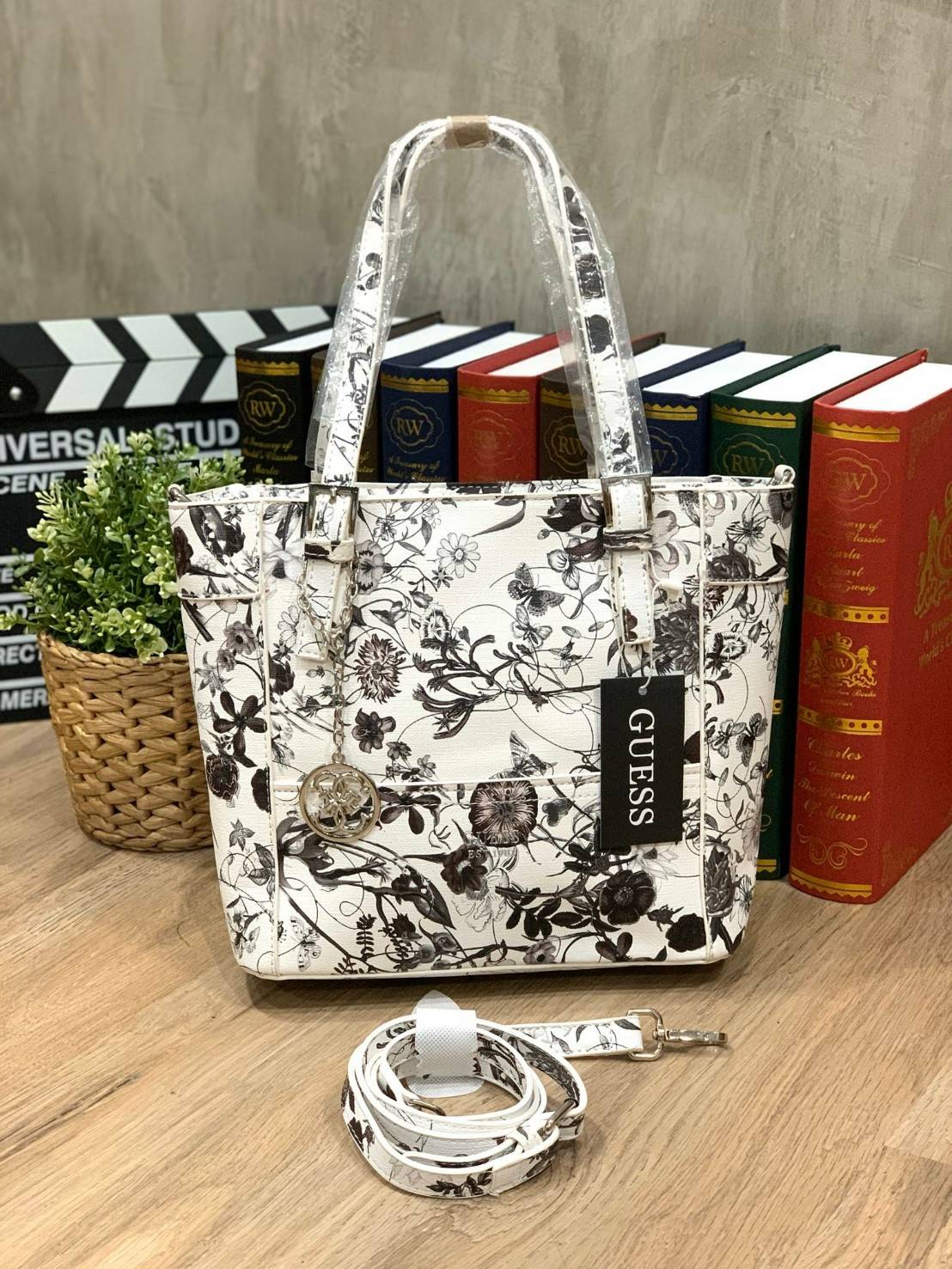 GUESS Women's Medium Floral Tote Bag กระเป๋าถือ คล้องไหล่หรือสะพาย ขนาดกลาง วัสดุหนังpu ลายดอกไม้ชนิดต่างๆรอบใบ เปิดปิดใช้งานด้วยซิปเดียวด้านบน ภายในมีกว้างใส่กระเป๋าสตาวค์ยาว มินิไอแพคได้ หูจับและสายสะพายปรับระดับได้ มาพร้อมกุญแจโลโก้guess สวยน่ารัก