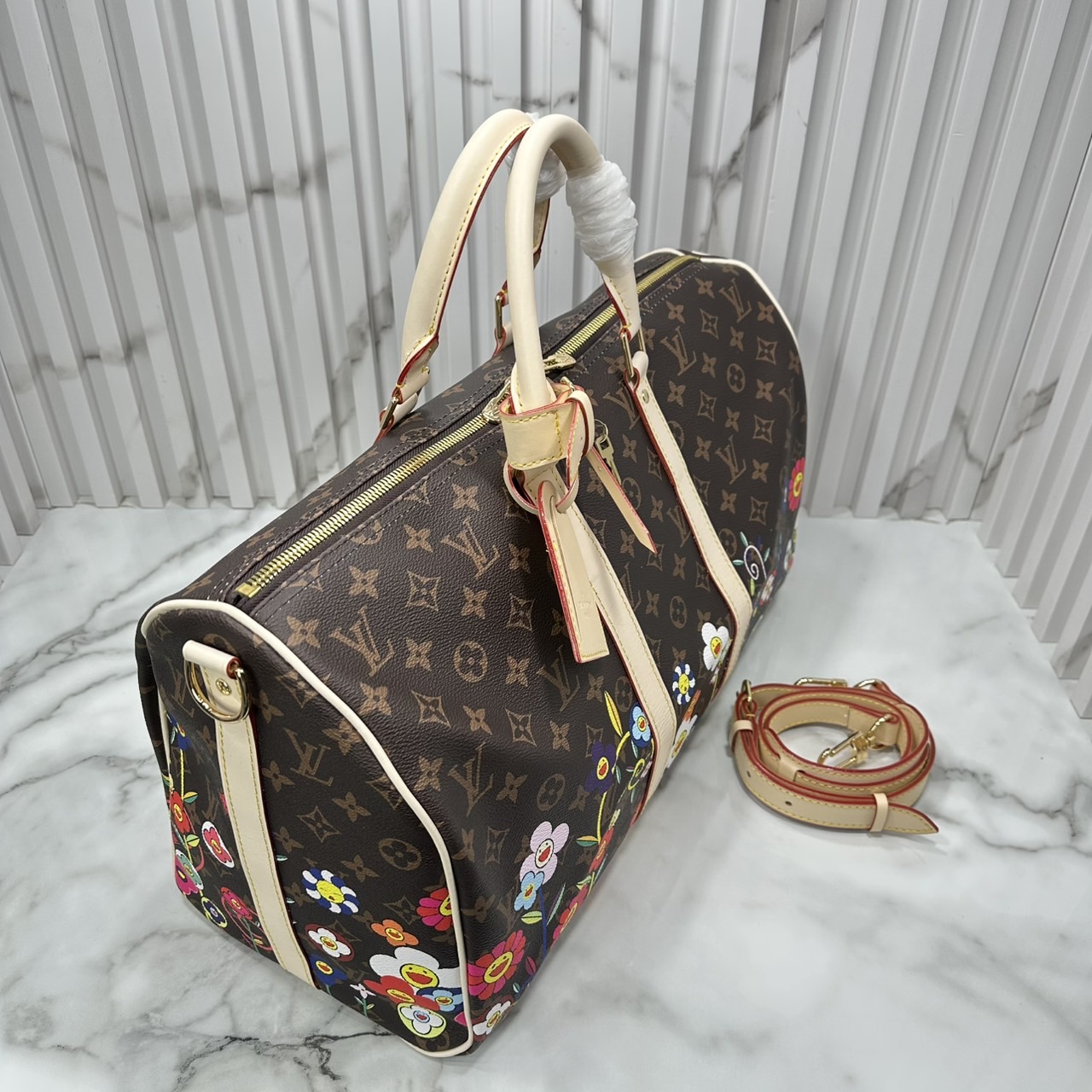 LV x TM Keepall Bandoulière 45 Bag Monogram Flower กระเป๋าเดินทางคอลเลกชันสุดพิเศษ สวยคลาสสิกมีชีวิตชีวา สีสันสดใสสไตล์ superflat สุดไอคอนิกของ Takashi Murakami ด้วยโมโนแกรมดอกไม้หลากสี ปรับดีไซน์ให้ดูสนุกสนาน