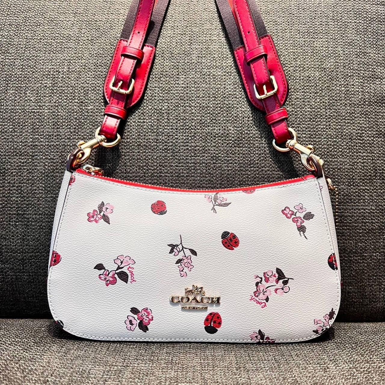 COACH C7973 JES BAGUETTE WITH LADYBUG FLORAL PRINT คอลเลคชั่นใหม่ล่าสุด พร้อมเสิร์ฟความสวยถึงบ้านเช่นเคย!! กระเป๋าสะพายทรงบาแกตต์ ดีไซน์ย้อนยุค ที่แอบแฝงความเรียบหรูดูแพงอยู่ในตัว โดดเด่นด้วยสายสะพายเส้นใหญ่ โทนสีคอนทราส ทำให้ไอเท็มนี้ดูมีลูกเล่นมากขึ้น ว