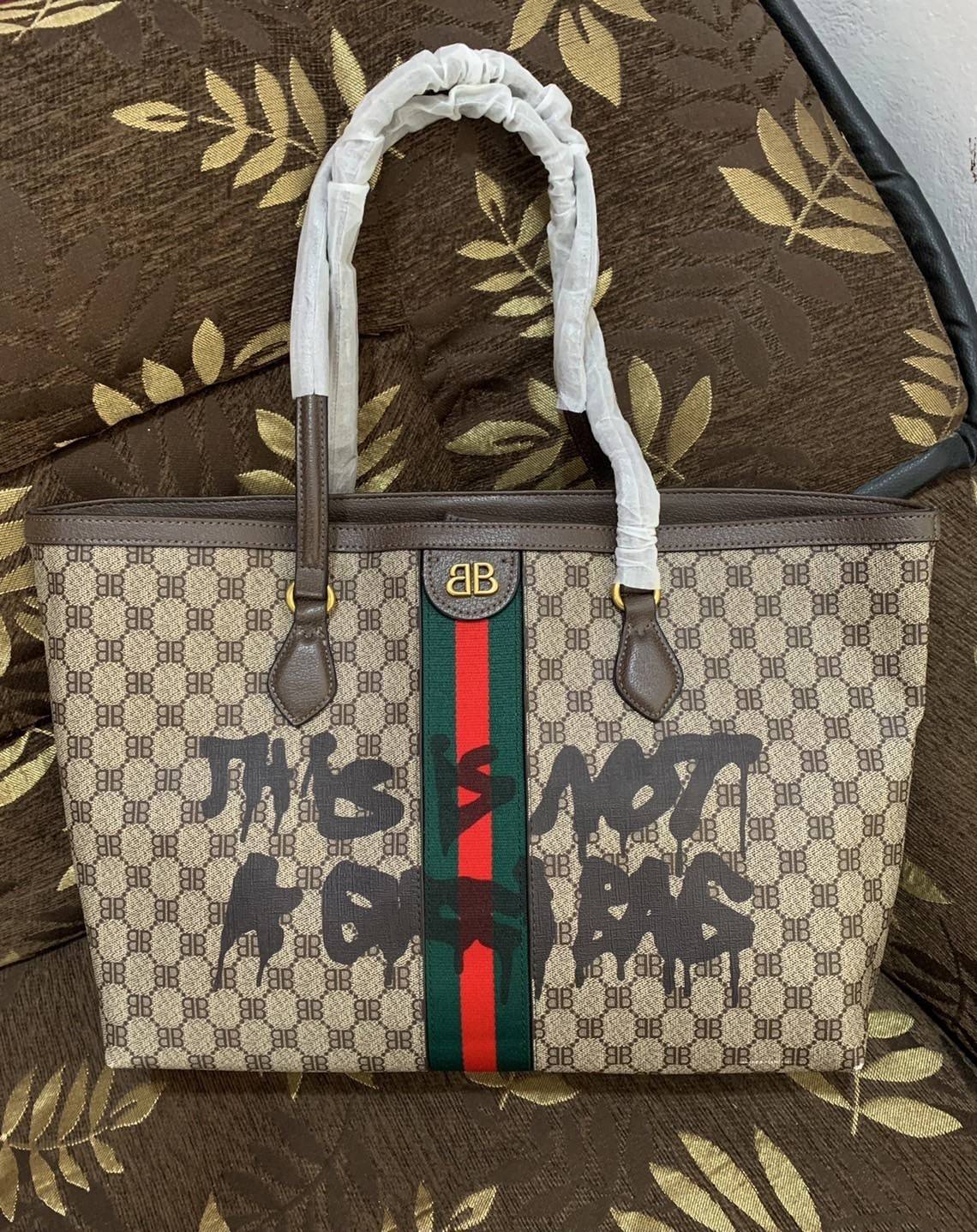 Gucci x Balenciaga The Hacker Project Graffiti Tote กระเป๋าช้อปปิ้งทรงโท้ท โดดเด่นด้วยลวดลายเพ้นท์กราฟฟิตี้ ใบใหญ่ จุสัมภาระได้อย่างจุใจ