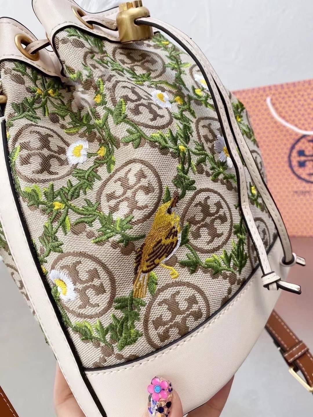 TORY BURCH T MONOGRAM JACQUARD EMBROIDERED BUCKET BAG ครั้งแรกกับโมโนแกรม ที่ได้รับแรงบันดาลใจมาจากโลโก้สุดคลาสสิก กลับมาอีกครั้งในรูปแบบของ ลวดลาย T Monogram ที่ผสมผสานความร่วมสมัยเข้ากับความเป็นเอกลักษณ์ของแบรนด์เข้าไว้ด้วยกัน โดยเป็นการนำเอาลวดลาย T Mo