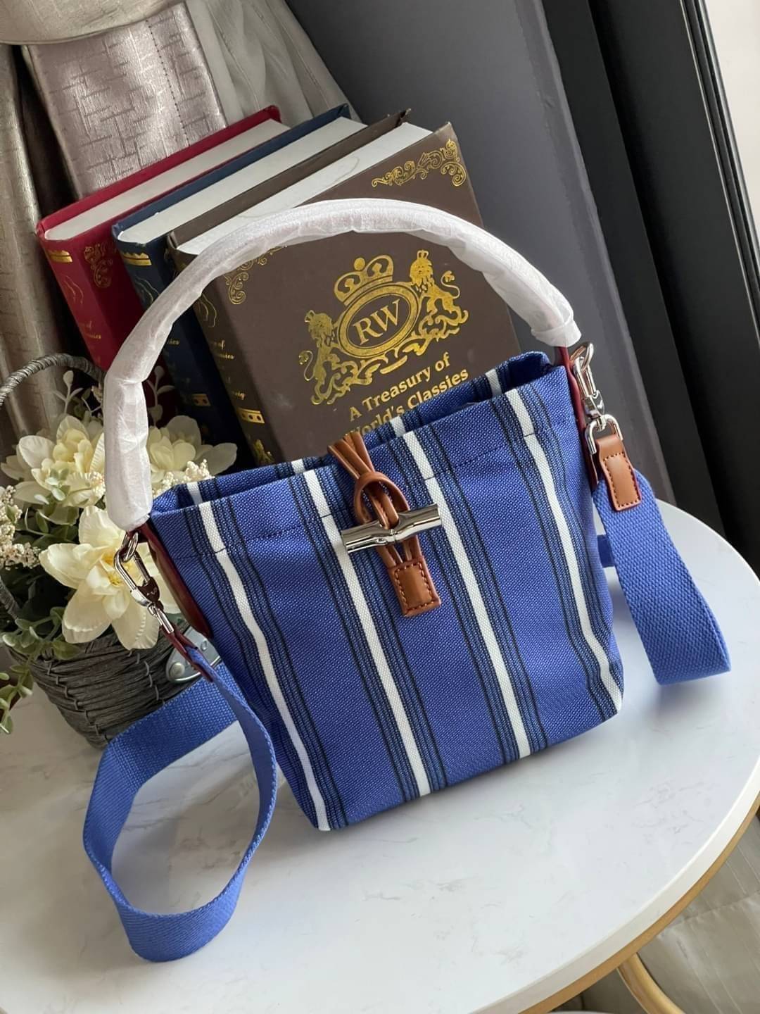 LONGCHAMP ROSEAU ESSENTIAL RAYÉ Bucket bag S - Blue สำหรับใครที่ต้องการกระเป๋าแบบใช้งานได้ในหลาย ๆ โอกาส สีสันกระเป๋าสามารถแมทช์ได้ง่ายกับเสื้อผ้า Longchamp รุ่นนี้สามารถตอบโจทย์ เป็นกระเป๋าที่ขนาดกำลังพอดี