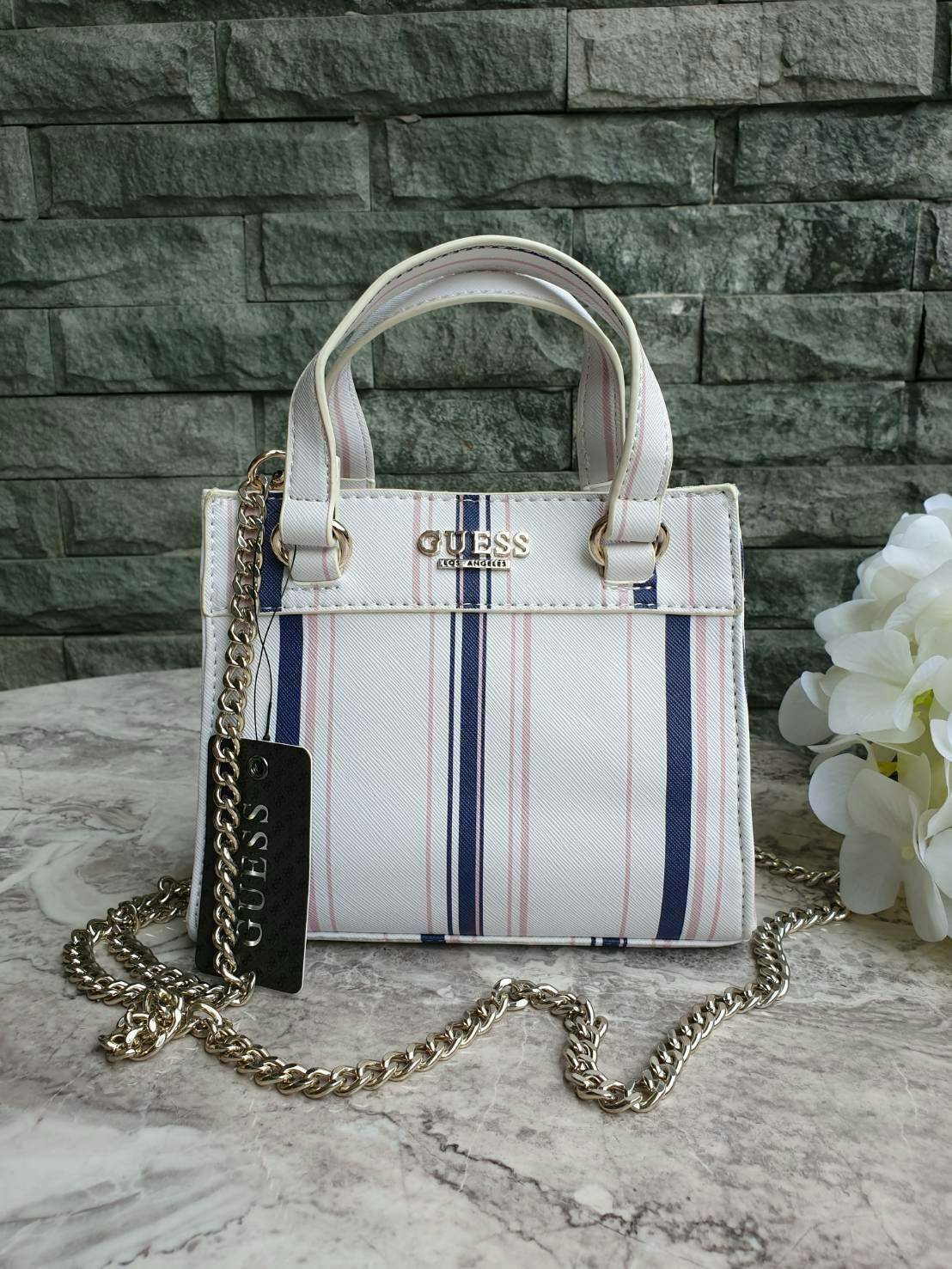 GUESS TAYLOR MINI SATCHEL CROSSBODY BAG กระเป๋าสะพายใบเล็ก สไตล์ สวยหรู คุณหนู ไฮโซ น่ารักมากๆ วัสดุหนังpu เย็บลายตาราง หนังนิ่ม จับนุ่มมือ และ ลายทาง หนัง saffiano ตั้งอยู่ทรง แบบน่ารักไม่ซ้ำใคร ด้านหน้าประดับโลโก้แบรนด์ อะไหล่ทอง มาพร้อมสายโซ่ ถอดออกได้