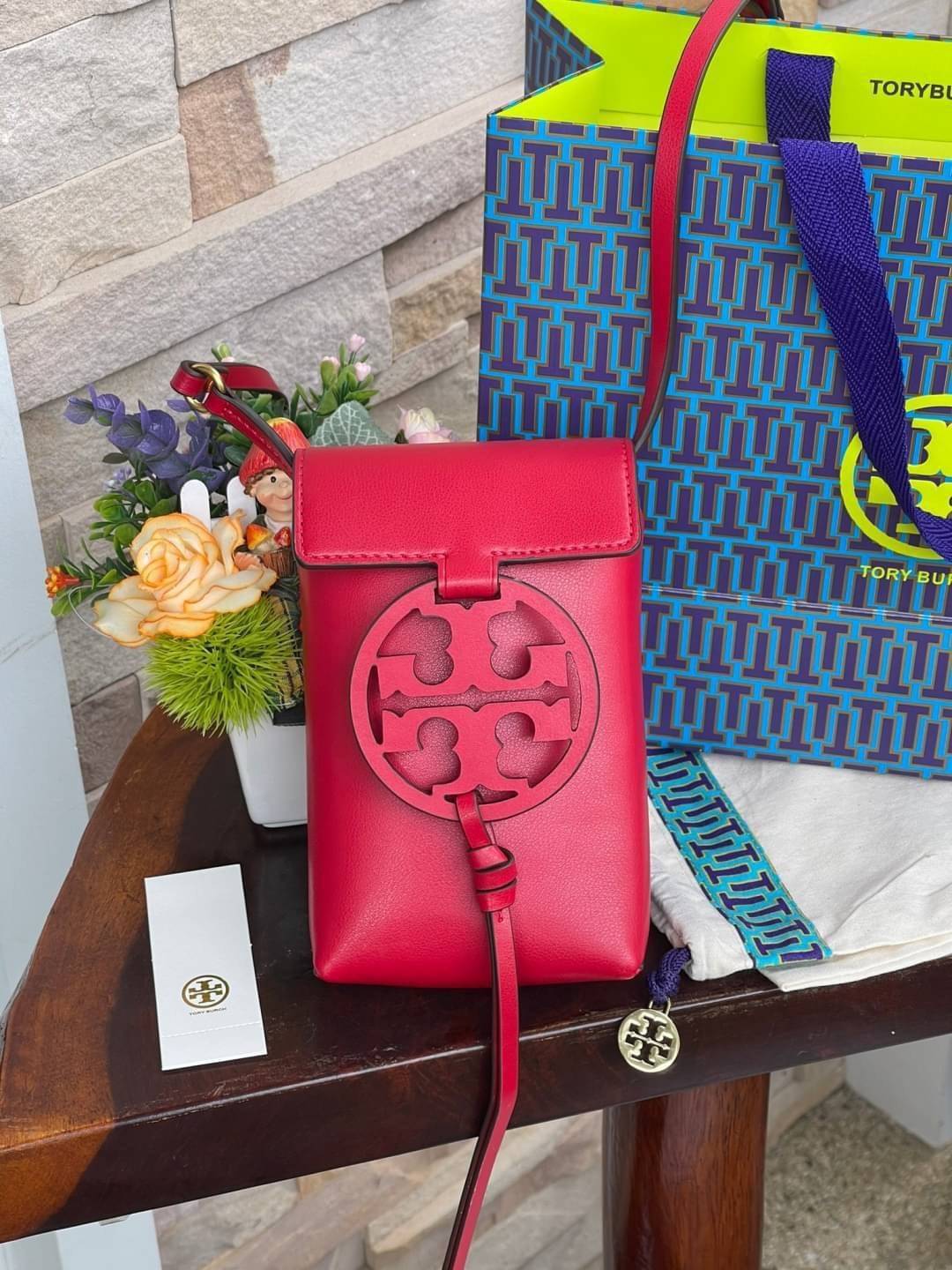 TORY BURCH MILLER METAL PHONE CROSSBODY อีกหนึ่งกระเป๋าใส่มือถือรุ่นฮิตที่เชื่อว่าหลาย ๆ คนต้องเคยเห็นผ่าน ๆ ตามาอย่างแน่นอน กับแบรนด์ Tory Burch ดีไซน์กระเป๋าทรงฝาพับแม่เหล็กใช้งานง่าย มาพร้อมดีเทล Logo สีเดียวกับเฉดสีของกระเป๋า แต่ยังมีความน่ารักด้วยทรง