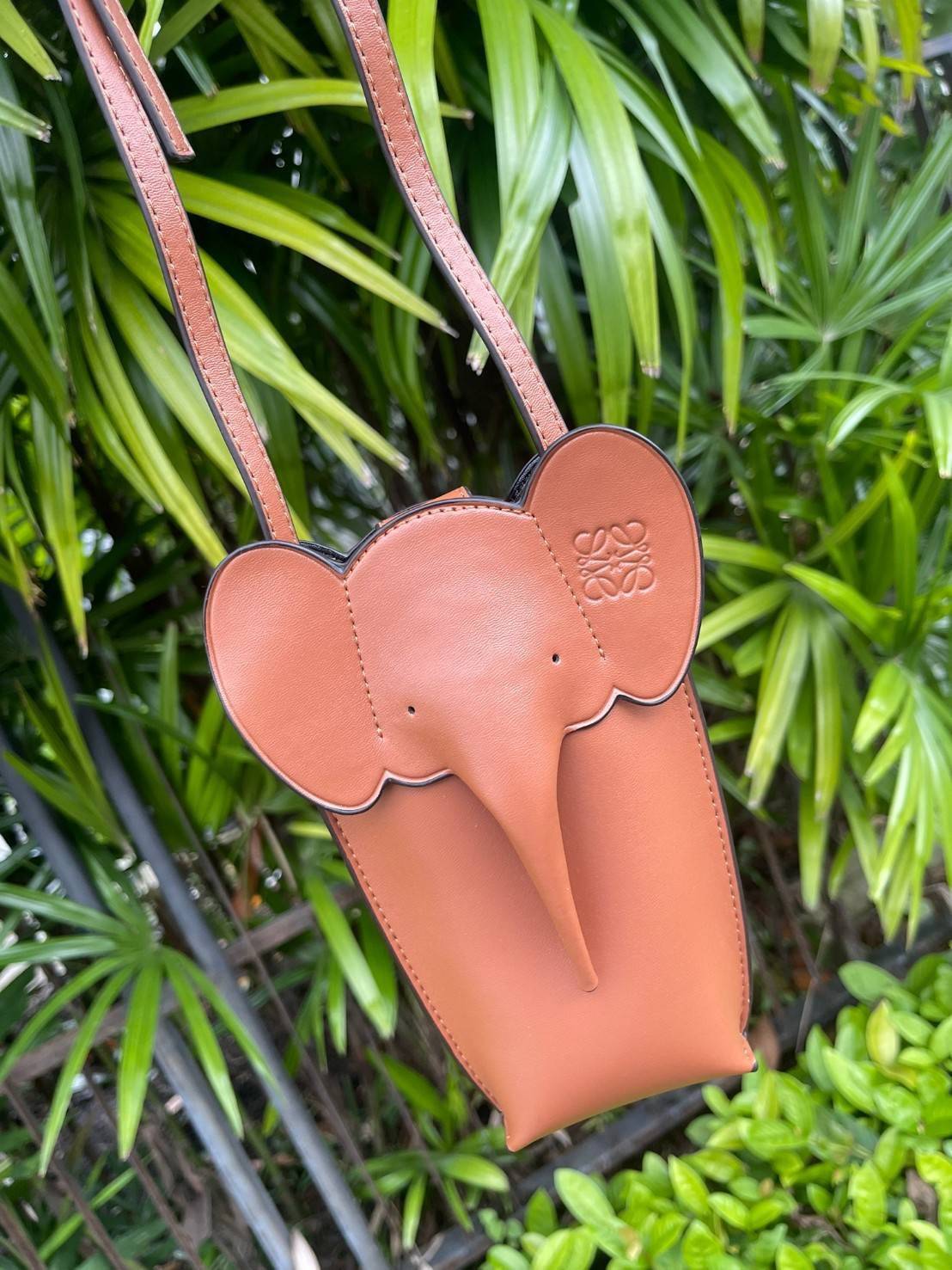 Loewe Leather Elephant Phone Holder แบรนด์หรูจากประเทศสเปนอย่าง โลเอเว่ (LOEWE) หลายๆคนคงนึกถึงกระเป๋ารูปทรงช้างขนาดเล็ก ที่เป็นเหมือนหนึ่งในซิกเนเจอร์ของแบรนด์ มีทั้งแบบสะพายข้าง แบบถือ รวมไปถึงในแบบเครื่องหนังชิ้นเล็กอย่างกระเป๋าใส่มือถือรุ่นนี้ ผลิตจาก