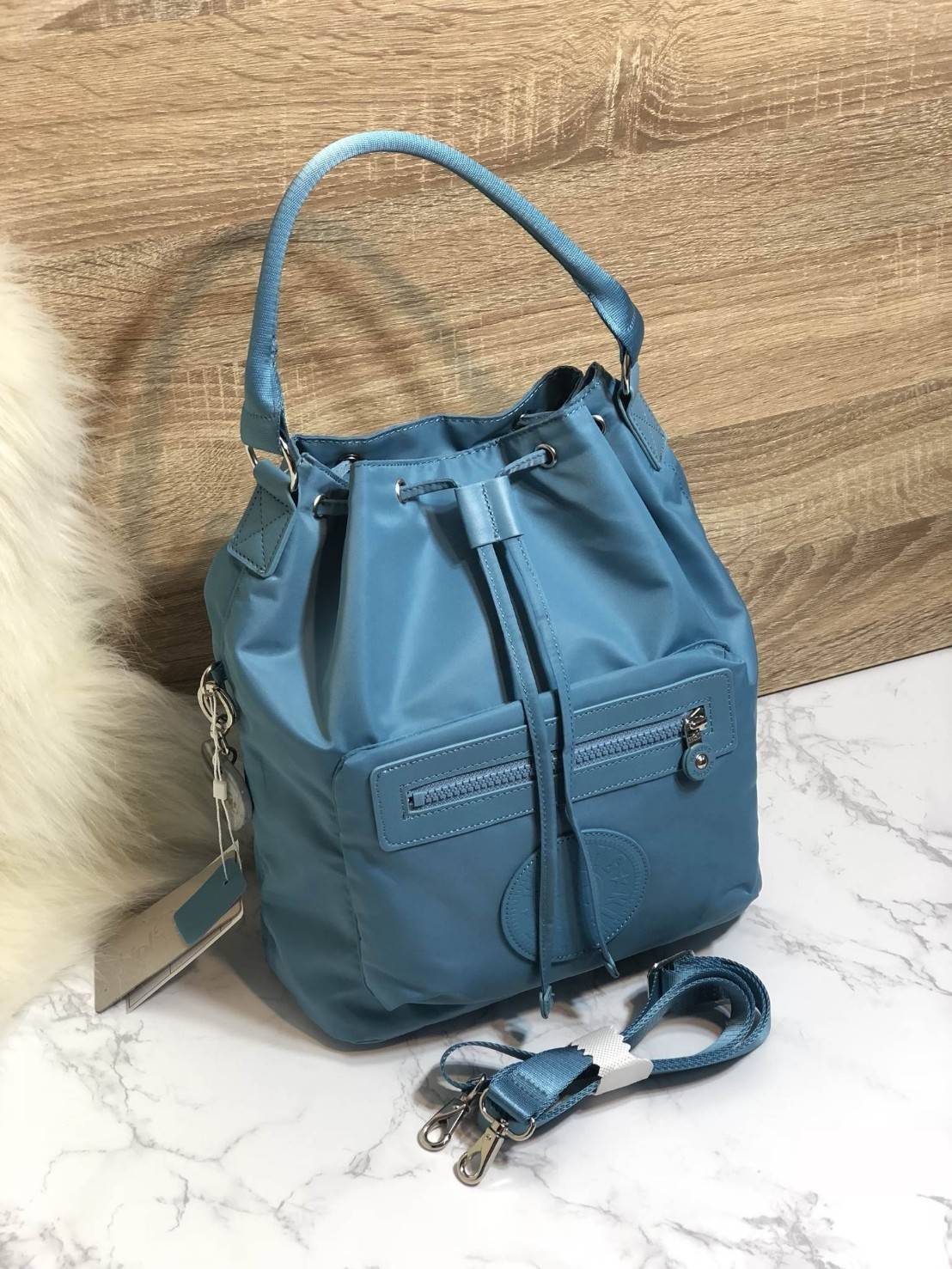 Kipling 2Way Bucket Bag กระเป๋าถือหรือสะพาย 2Way รุ่นใหม่ทรงขนมจีบวัสดุ Nylon & Polyester 100% น้ำหนักเบา ถือและสะพายได้หลายแบบจะใช้สายยาวสะพาย Crossbody หรือใช้สายคู่สะพายหลังแบบเป้ก็ดูดี หูจับถนัดมือสะพายไหล่ได้ เปิดปิดแบบ Drawstring พร้อมกระดุมแม่เหล็ก