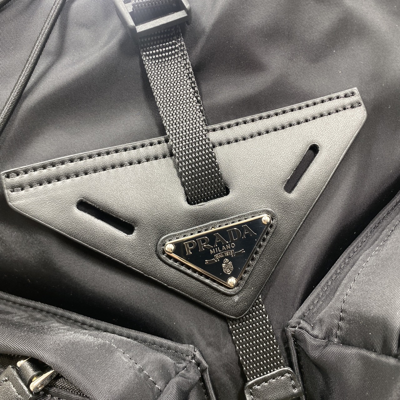 ORI หนังแท้ | Prada Re-Nylon and leather backpack กระเป๋าสะพายหลัง เป้ผ้าไนลอนรูปทรงเรขาคณิตเรียบหรู สถาปัตยกรรมและเส้นสาย ผสมผสานรูปทรงและวัสดุที่ตัดกันอย่างลงตัว