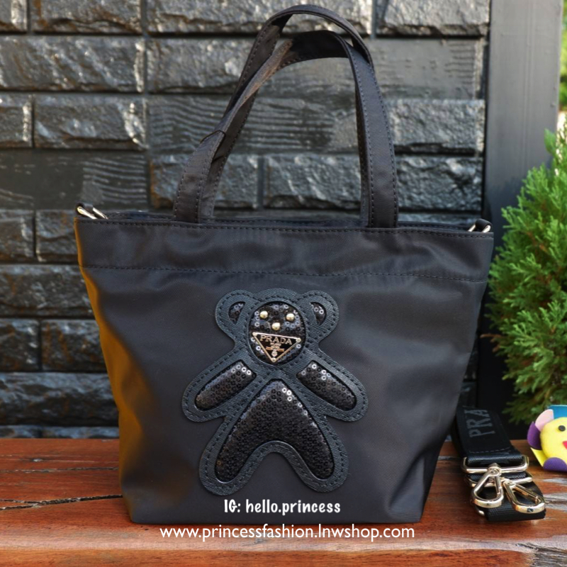 PRADA NYLON MINI TOTE BAG กระเป๋าสะพายขนาดมินิทรง TOTE พรีเมี่ยมกิ้ฟจากเคาน์เตอร์ต่างประเทศรุ่น Limited edition ที่ฮอตสุดๆในขณะนี้ วัสดุเป็น Nylon ตามแบบฉบับของแบรนด์ ขนาดมินิกำลังดี น้ำหนักเบา ด้านหน้าเป็นลายหมีปั๊กกลิ้ตเตอร์โลโก้แบรนด์อะไหล่ทองหรู ภายใน
