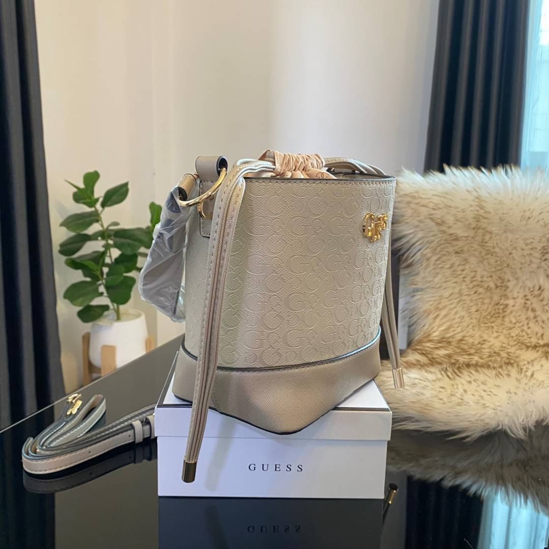 Guess Agata Bucket Handbag กระเป๋ารุ่นใหม่ล่าสุดทรงถังสุดน่ารัก พิมพ์ลายรอบใบ วัสดุ Saffiano PU คุณภาพดี นิ่ม น้ำหนักเบา ด้านหน้าประดับด้วยโลโก้แบรนด์สวยโดดเด่น เปิด-ปิดด้วยเชือกหนังใช้หูรูดปลายเชือกประดับอะไหล่ทองสะดวกใช้ ด้านในโล่งกว้างมีช่องเล็กสำหรับใ