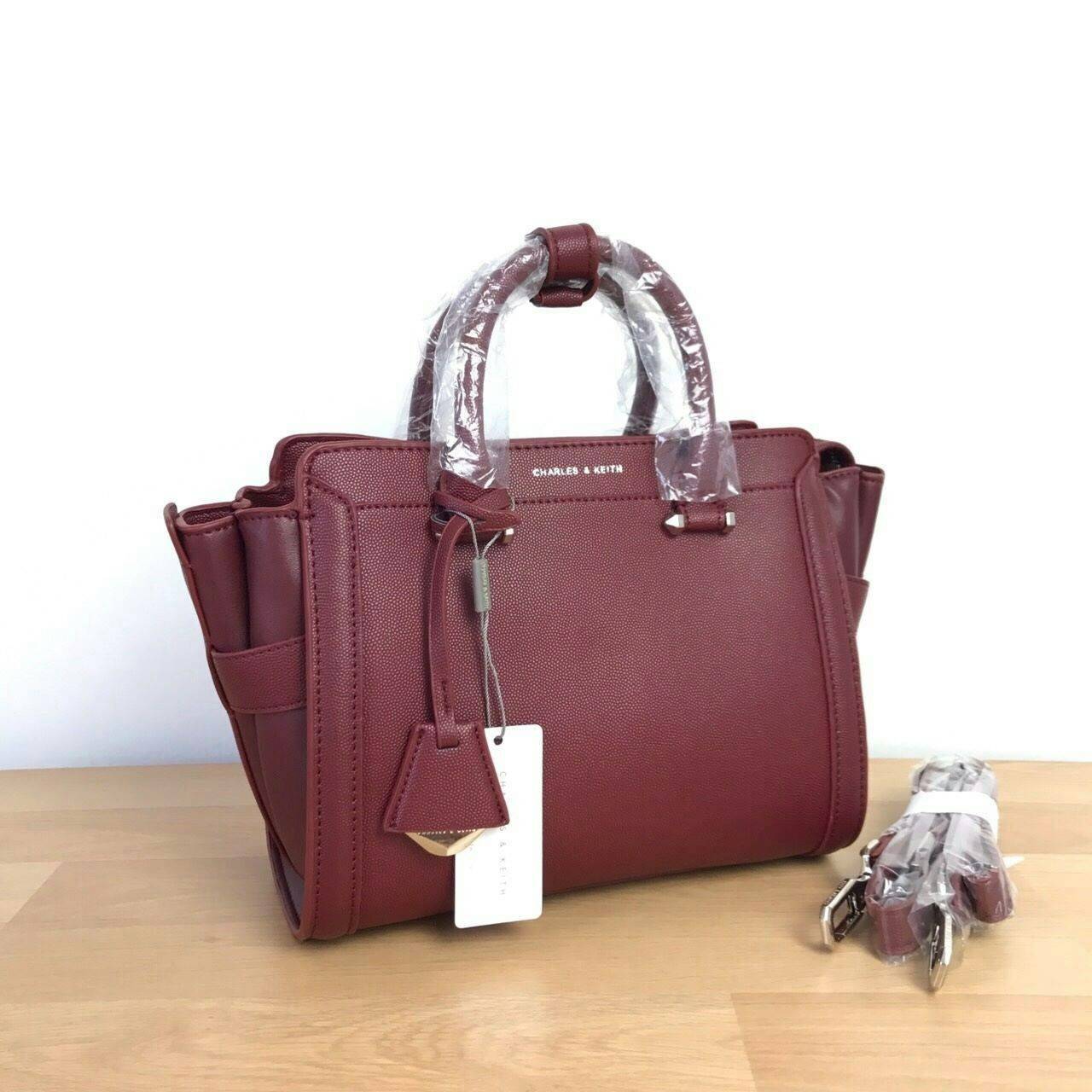 CHARLES & KEITH TRAPEZE BAG Best sellwr ! กระเป๋าถือหรือสะพายรุ่นยอดนิยมดีไซน์สวยหรูวัสดุหนัง คาเวียร์อยู่ทรง ด้านข้างเเต่งหนังช่องตัดดูมีดีเทล ด้านหน้าสกรีนโลโก้ ด้านหลังมีช่องซิป เปิดปิดด้วยซิปหัวซิป ปัํ๊มโลโก้ หูจับเเข็งแรง พับลงได้ พร้อมสายสะพายหนังปร