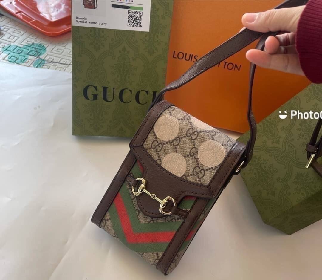VIP 】GG CANVAS AND LEATHER CROSS-BODY PHONE BAG พร้อมส่งที่ไทย Brown canvas Brown Ophidia GG Supreme mini bag from GUCCI featuring an adjustable shoulder strap, a foldover top, a GG Supreme pattern, a Web stripe to the front and a gold-tone Double G plaqu
