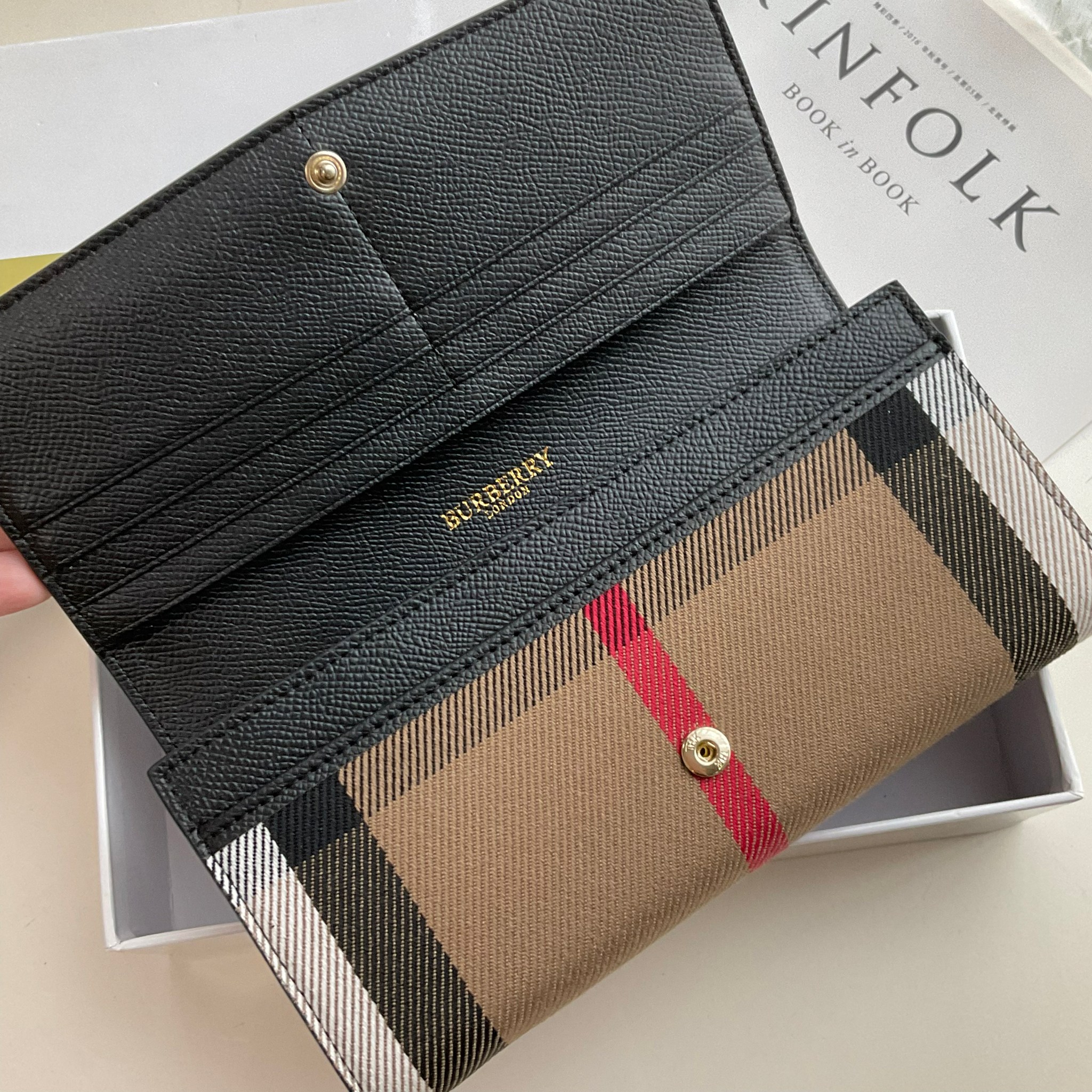 กระเป๋าสตางค์รับทรัพย์ ทรงหรู จากงาพรีเมี่ยมกิ๊ฟ Limited Edition จาก BURBERRY กระเป๋าสตางค์ใบยาวแบบพับกระดุม ทูโทนด้วยหนังแท้คาดผ้าลาย vintage ด้านในมีช่องใส่ธนบัตรยาวทั้งสองฝั่ง ช่องใส่บัตรได้อย่างน้อย 12 ช่อง และช่องเปิดด้วยซิปปั้มแบรนด์อะไหล่ทองสุดหรู 