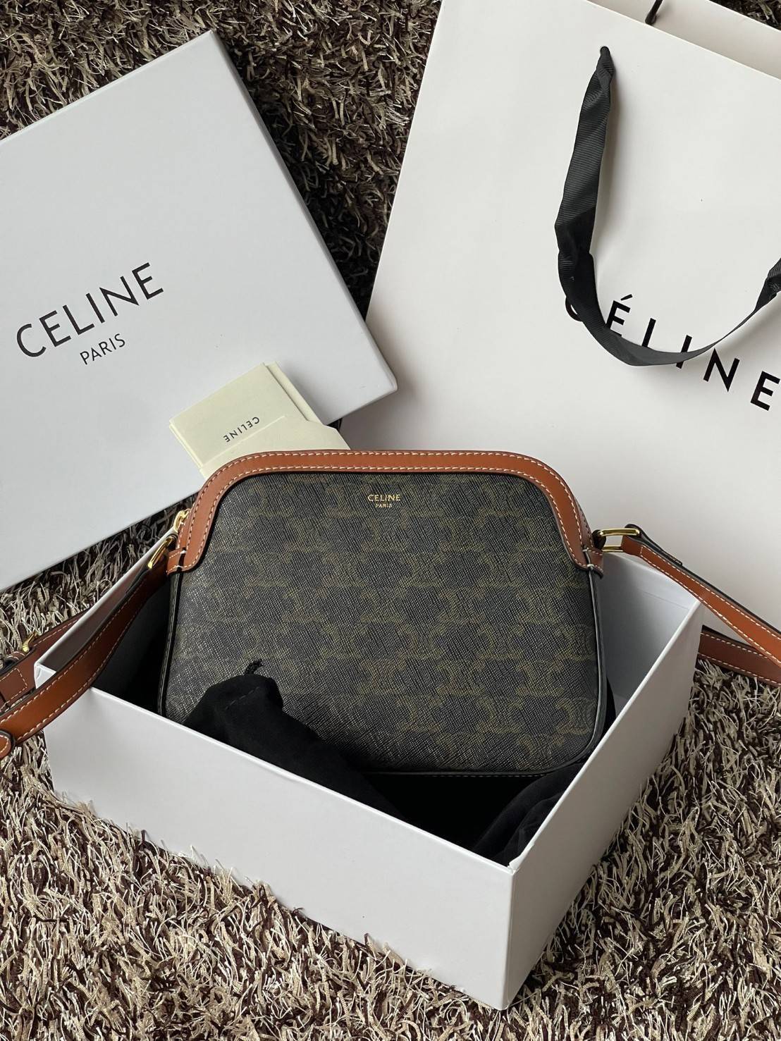 CELINE Triomphe Canvas Small Camera กระเป๋าสะพายไหล่สุดเก๋ใบนี้ผลิตจากผ้าใบเคลือบอย่างดีพร้อมขอบหนังสีน้ำตาล มาพร้อมสายสะพายหนังปรับระดับได้พร้อมฮาร์ดแวร์สีทองและซิปด้านบน ภายในบุด้วยผ้าสีน้ำตาล ลวดลาย triomphe อันเป็นเอกลักษณ์ของแบรนด์ และเป็นกระเป๋าสะพา