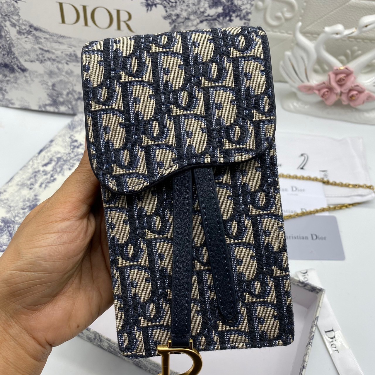 หนังแท้ DIOR PHONE BAG / DIOR PHONE HOLDER BAG กระเป๋าใส่โทรศัพท์เอกลักษณ์ของความหรู สายสะพายโซ่อะไหล่ทอง วัสดุหนังแท้และผ้า Jacquard อย่างดีสวยงามที่สุด ผสมผสานความสง่างามและคลาสสิกที่เข้ากับยุคสมัย ด้านหน้าโดดเด่นด้วยซิกเนเจอร์แบรนด์ เป็นอีกหนึ่งรุ่นที่