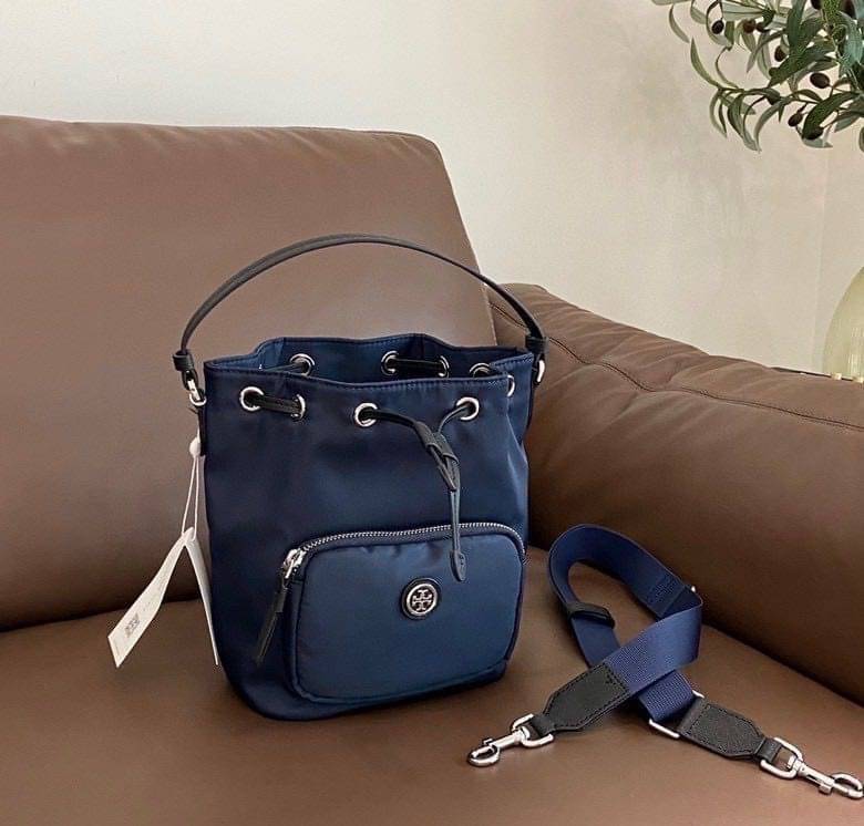 Tory Burch Virginia Nylon Bucket Bag / Tory Burch logo-plaque bucket bag กระเป๋าสะพายทรงบัคเก็ต เปิด-ปิดหนังรูดปากกระเป๋า มีหูหิ้วในตัว คล้องแขนเก๋ๆ ภายในเป็นช่องโล่ง มีช่องย่อย ใส่ของสำคัญจุกจิกได้ มีสายครอส จะสะพายไปไหนก็ได้ทุกโอกาส สวยเลิศทุกสี พร้อมส่