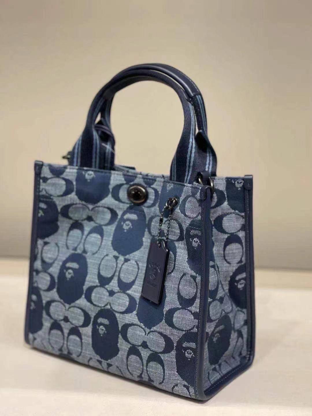 Coach Bape X Coach Tote 22 In Signature Jacquard กระเป๋าถือและครอสบอดี้โท้ทมินิไซส์ รุ่นใหม่สุดฮอต!! ใบจริงคือน่ารักม้ากกกก!! สวยอยู่ทรง มี 2 สี น่ารักน่าใช้ วัสดุหนังแคนวาส มาพร้อมหูจับในตัวและสายสะพายข้าง ถอดออกหิ้วเก๋ๆก็ได้ หรือสะพายถ่ายรูปชิคๆก็ดูดี ล