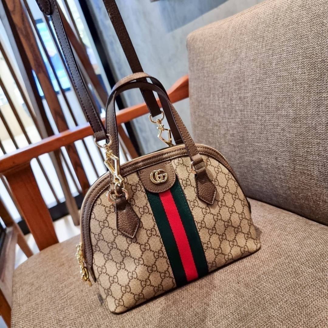 GC CLASSIC SATCHEL BAG กระเป๋าถือ/สะพายทรงโดม รุ่นหายาก สวยคลาสสิค แถมฟรี!! โบว์ผ้าลายแบรนด์ สำหรับตกแต่งหูกระเป๋า ผูกเป็นโบว์ หรือพันถนอมหูกระเป๋าก็เพิ่มดีเทลความหรูได้ วัสดุหนังแคนวาส ดีไซน์แถบคาดโดดเด่น เปิด-ปิดกระเป๋าด้วยซิป หัวซิปตัว G อะไหล่สีทอง เล