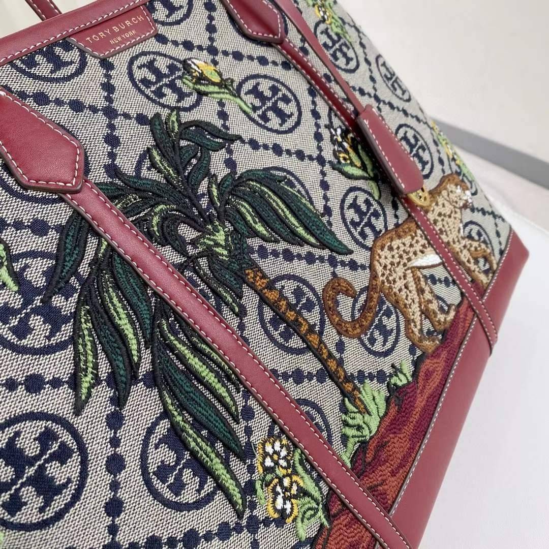 Tory Perry Embroidered T Monogram Triple Compartment Tote Bag เป็นแพทเทิร์นที่ได้รับแรงบันดาลใจจากการควิลท์สไตล์เพนซิลเวเนียดัตซ์ดั้งเดิมและเฉลิมฉลองโลโก้อันเป็นสัญลักษณ์ของแบรนด์ วัสดุผ้าแจ็คการ์ดแบบทอหนัง อะไหล่ทอง โดดเด่นด้วยลายเสือชีร์ต้าร์ งานเย็บปัก
