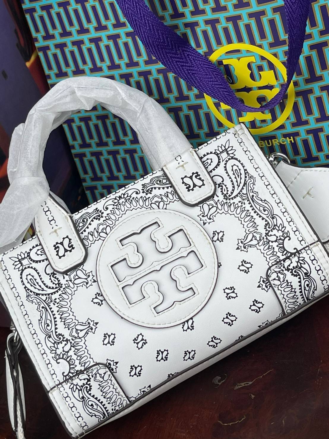 Tory Burch Ella Printed Leather Micro Tote Bag กระเป๋าขนาดมินิใบนี้บอกเลยว่าสไตล์เก๋และแปลกตาเลยทีเดียว กระเป๋าทรงสี่เหลี่ยมขนาดมินิ มีสายสะพายที่ออกแบบมาเข้ากับกระเป๋าสำหรับสะพายข้าง ลวดลายและสีสันบนกระเป๋ามีเอกลักษณ์ที่แสดงถึงความเป็นศิลปะแบบทอรี่โดยเฉพ