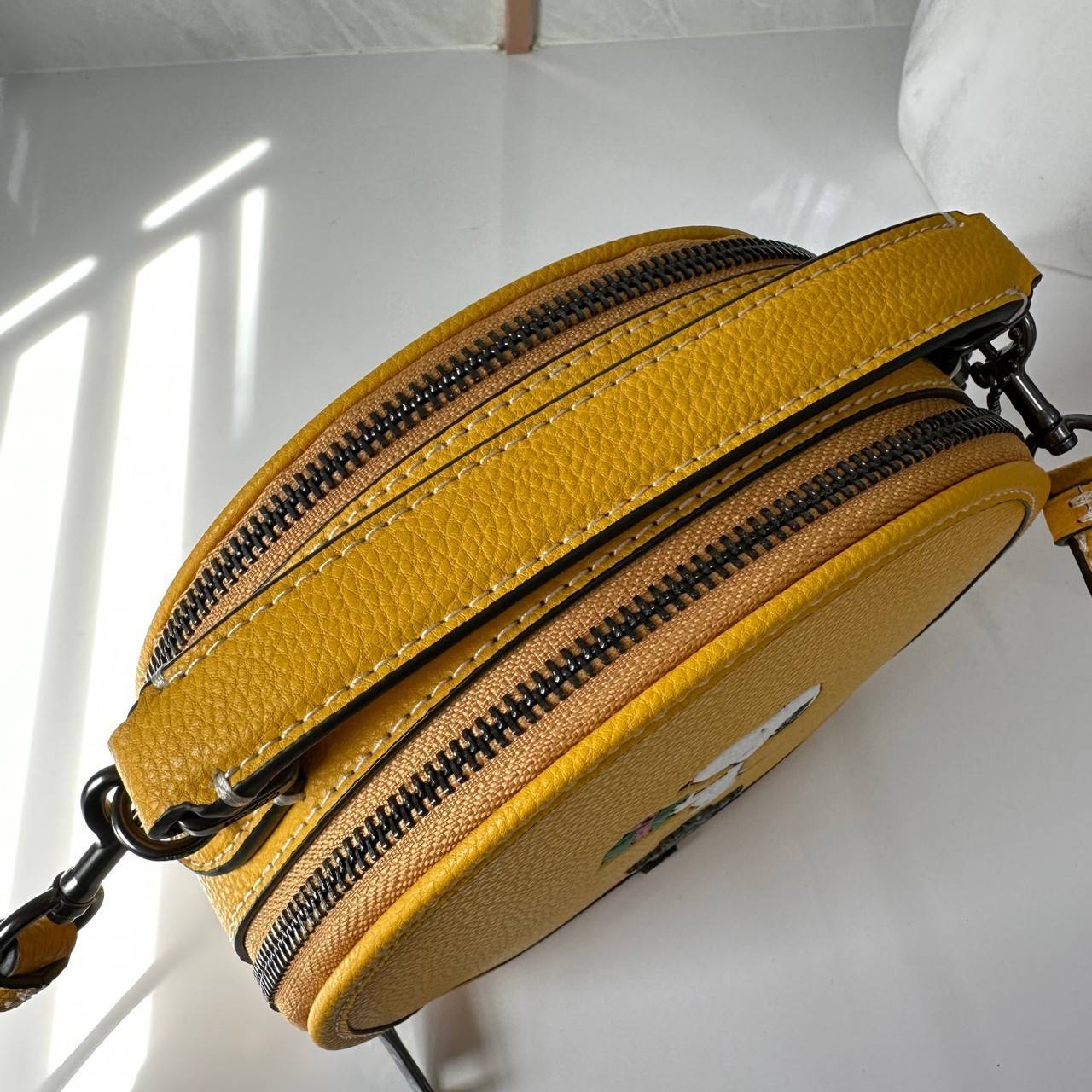 COACH X PEANUTS CANTEEN CROSSBODY WITH SNOOPY PRESENT MOTIF (CE845,CF290) กระเป๋าสะพายข้างทรงกลมไซส์มินิ มีหูจับ วัสหนังแท้ ด้านหน้าโดดเด่นด้วยรูปการ์ตูนSnoopy