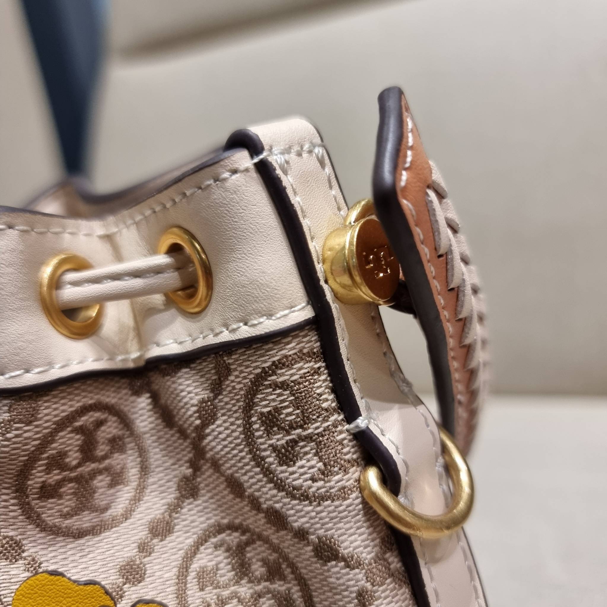 TORY BURCH MINI T MONOGRAM FLORAL BUCKET BAG คอลเลคชั่นใหม่ พร้อมเสิร์ฟความสวยให้ถึงบ้าน!! กระเป๋าบัคเก็ตทรงยอดนิยม ไซส์มินิ ดีไซน์ใหม่ล่าสุด สไตล์งานคราฟ มีลูกเล่นประดับดอกไม้กับตัวกระเป๋า และตัวรูดสาย วัสดุผ้า jacquard ตัดสลับหนังแท้ หูจับและขอบกระเป๋าต