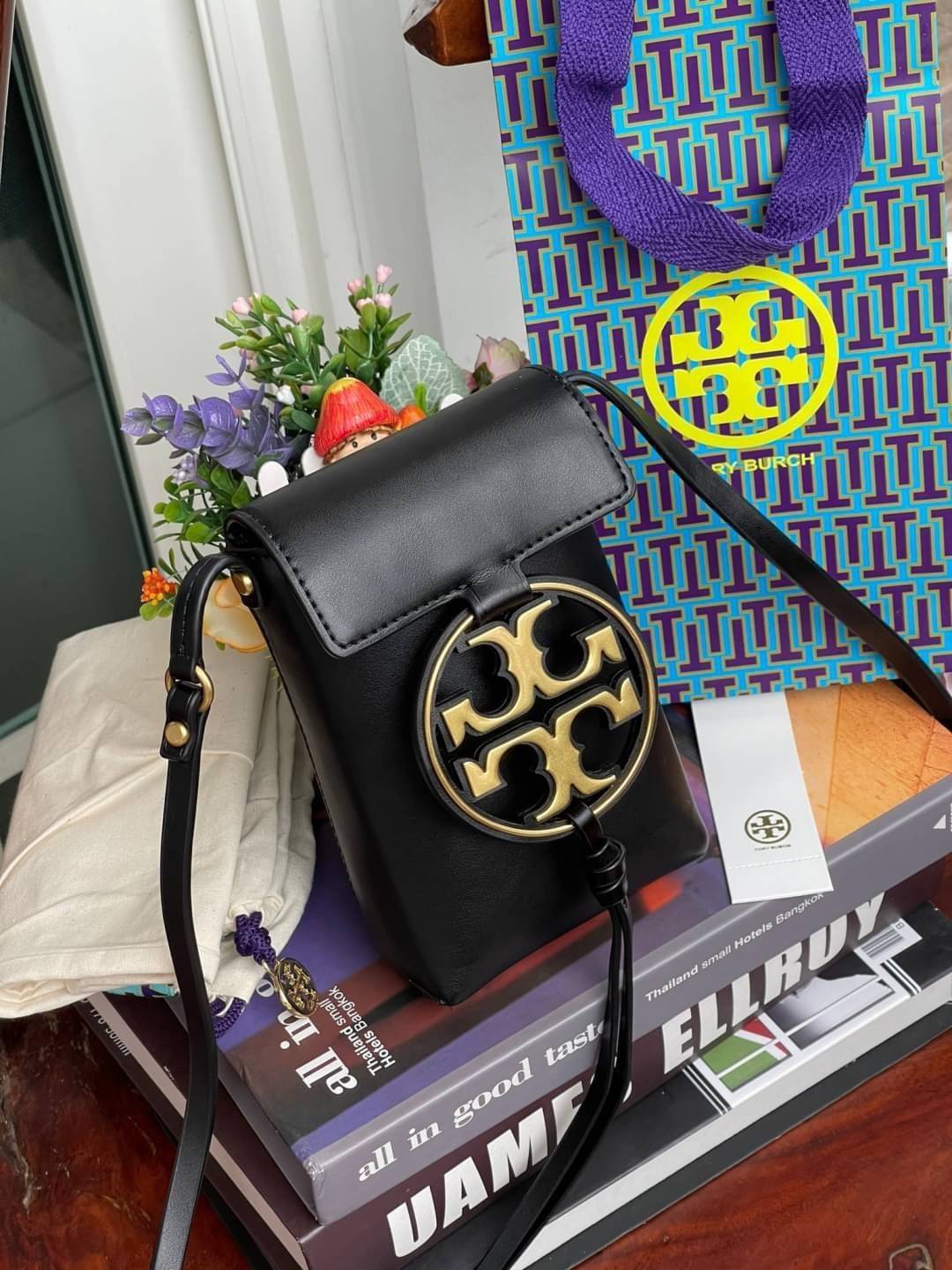 TORY BURCH MILLER METAL PHONE CROSSBODY อีกหนึ่งกระเป๋าใส่มือถือรุ่นฮิตที่เชื่อว่าหลาย ๆ คนต้องเคยเห็นผ่าน ๆ ตามาอย่างแน่นอน กับแบรนด์ Tory Burch ดีไซน์กระเป๋าทรงฝาพับแม่เหล็กใช้งานง่าย มาพร้อมดีเทล Logo แบรนด์โดดเด่นสีทองตัดกับหนังแกะสีดำ ดูหรูดูแพง! แต่