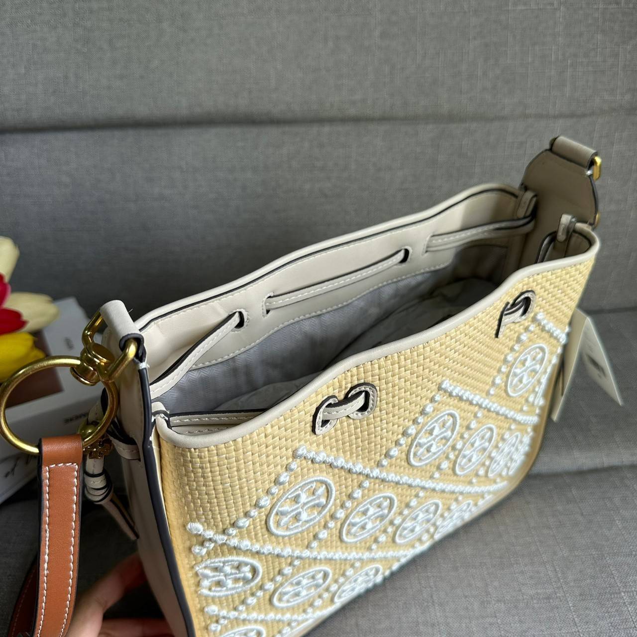 TORY BURCH T Monogram Straw Bell Bag กระเป๋าสะพายข้างรุ่นคลาสสิกที่ได้แรงบันดาลใจจากการควิลท์แบบดั้งเดิมของเพนซิลเวเนีย คอลเลกชันบ่งบอกถึงความมีสไตล์เหนือกาลเวลา รูปทรงเรียวโดดเด่น ปักทอลายแบรนด์อย่างสวยงาม เปิด ปิดด้วยเชือกรูด ด้านในช่องโล่งกว้าง ซับในผ้