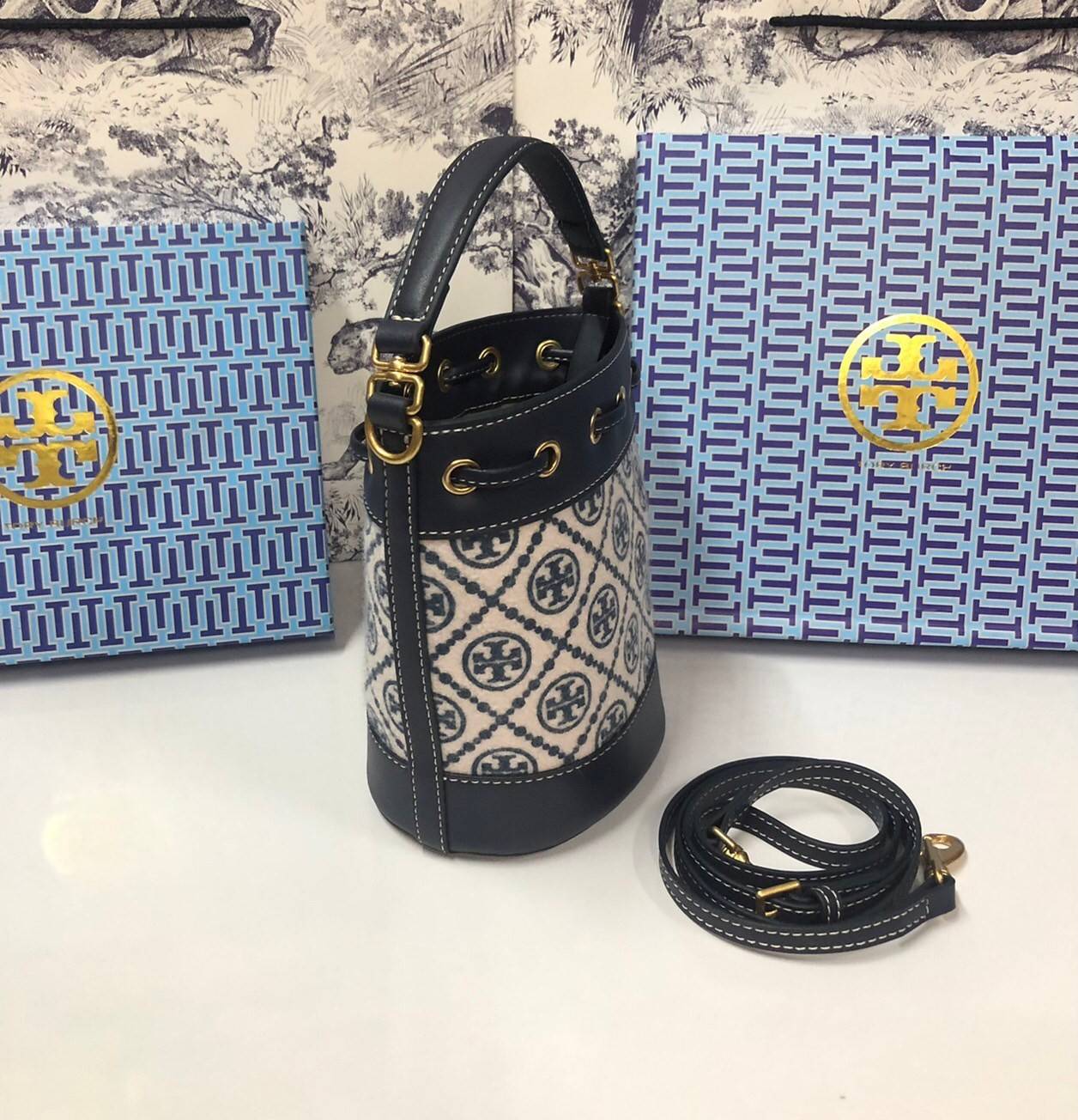 Mini : Tory Burch T Monogram Chenille Bucket Bag เปิดตัวอีกหนึ่งรุ่นกับกระเป๋าลาย T MONOGRAM รุ่นใหม่ล่าสุดจาก TORY BURCH พลาดไม่ได้กับโลโก้สุดคลาสสิก ลวดลาย T Monogram คือวัสดุ chenille หรือที่เรียกว่า ด้านไหมกำมะหยี่ มารังสรรค์ลงบนกระเป๋าBucketใบนี้ เป็