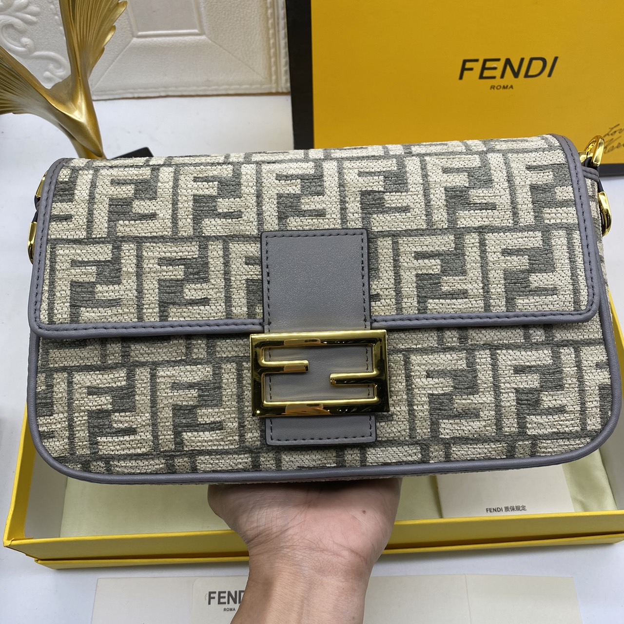 Fendi Baguette FF Tapestry Fabric Bag เกรดออริจินอล กระเป๋าทรง Baguette ขนาดกลาง วัสดุผ้าเซนิล พร้อมลวดลาย FF สีเทาเข้ม ปิดท้ายด้วยรายละเอียดหนังแบบทูโทนและประดับด้วยตัวล็อค FF โดดเด่นด้วยฝาปิดด้านหน้าตัวล็อคแม่เหล็กช่องด้านในบุด้วยผ้าหนังกลับพร้อมกระเป๋า