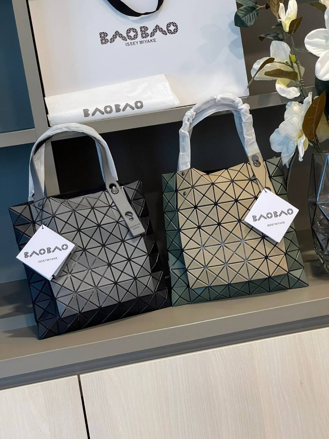 Baobao Issey Miyake Prism Kangaroo tote bag กระเป๋าถือทรงโท้ทที่ประดิษฐ์ขึ้นอย่างเชี่ยวชาญในญี่ปุ่น มาพร้อมแผงเรขาคณิตสำหรับการออกแบบที่ได้รับแรงบันดาลใจจากกระดาษพับ ซิลลูเอทอันเป็นเอกลักษณ์นี้ปิดท้ายด้วยสายรัดแบบอสมมาตร มีการพัฒนาโครงสร้างทรงสามเหลี่ยมเพ