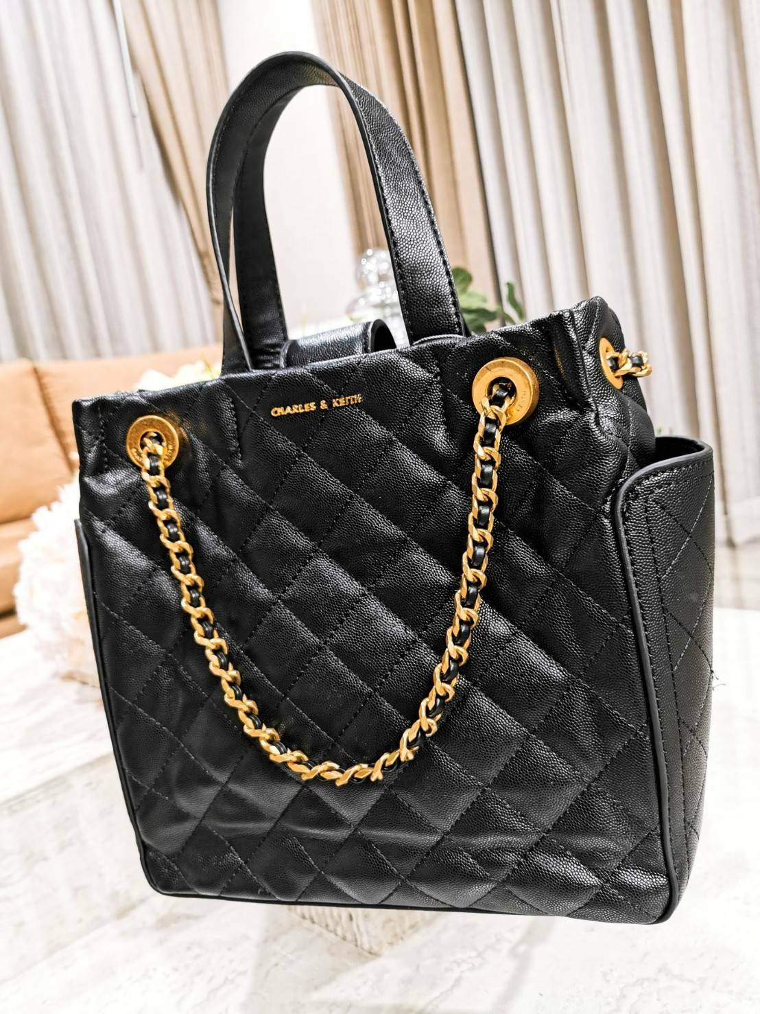 CHARLES & KEITH HANDBAG กระเป๋าถือหรือสะพายดีไซน์สวยหรูวัสดุหนังคาเวียร์อยู่ทรง ด้านหน้ามีโลโก้ ด้านข้างมีช่องใส่ของ มีหูจับถนัดมือ พร้อมสายสะพายโซ่มีที่รองบ่าสามารถใช้สายคู่สะพายไหล่หรือสายเดี่ยว Crossbody ได้ มีหมุดรองฐานกันรอย ภายในมีช่องซิปเเละช่องใส่