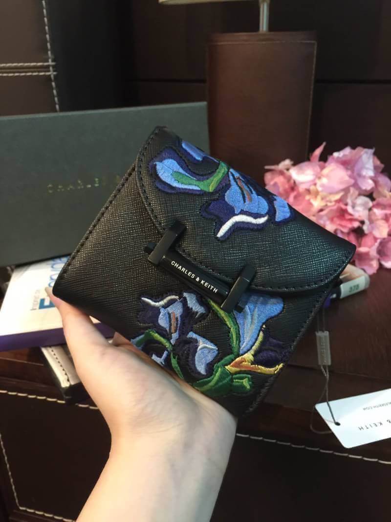 BEST SELLER! CHARLES & KEITH Peforated Wallet กระเป๋าสตางค์ใบสั้นพับ3ตอนรุ่นยอดนิยมวัสดุหนัง Saffiano สีดำประดับลายดอกไม้ Van Goh คลาสสิค ดีไซน์สวยเก๋ไม่ซ้ำใคร ด้านหน้าปั้มโลโก้เปิดปิดด้วยกระดุมเเม่เหล็ก ภายในมีช่องซิปสำหรับใส่เหรียญ หัวซิปปั้มโลโก้ มีช่อ