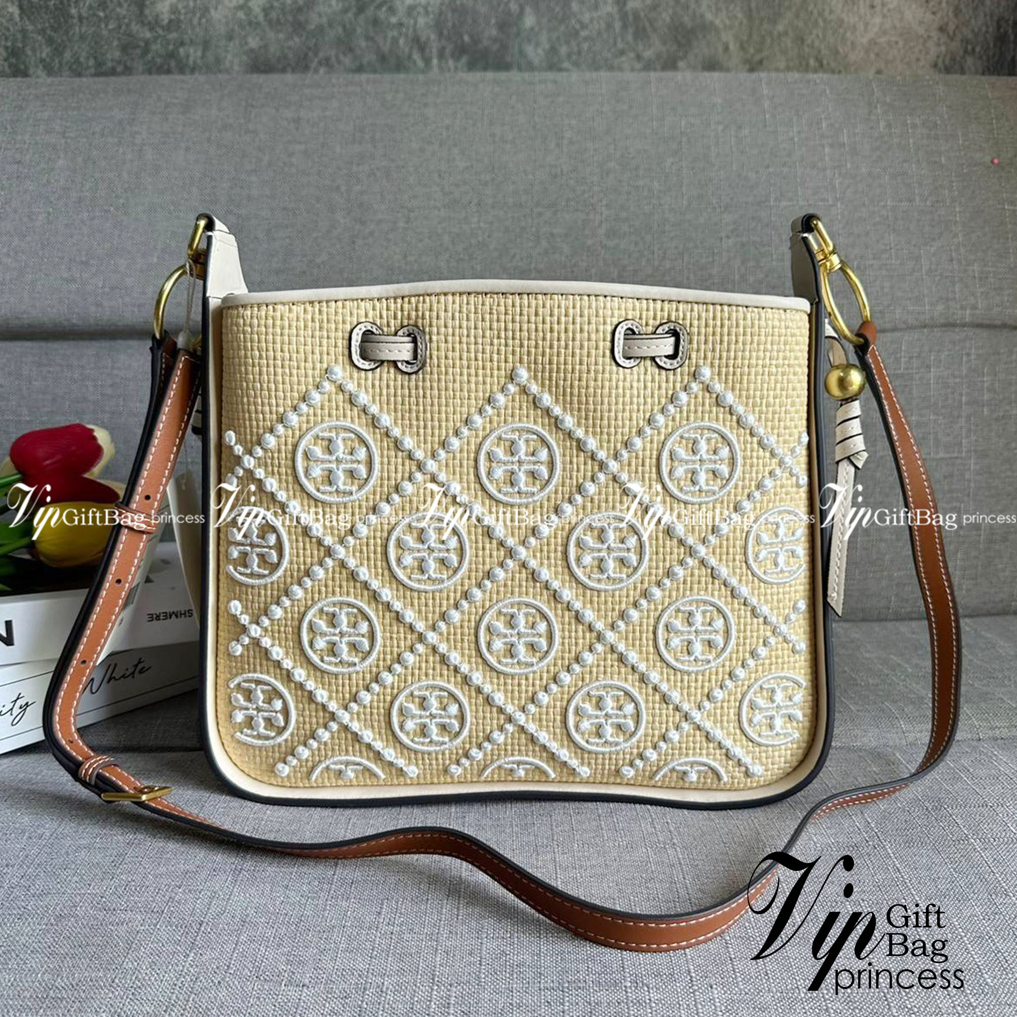 TORY BURCH T Monogram Straw Bell Bag กระเป๋าสะพายข้างรุ่นคลาสสิกที่ได้แรงบันดาลใจจากการควิลท์แบบดั้งเดิมของเพนซิลเวเนีย คอลเลกชันบ่งบอกถึงความมีสไตล์เหนือกาลเวลา รูปทรงเรียวโดดเด่น ปักทอลายแบรนด์อย่างสวยงาม เปิด ปิดด้วยเชือกรูด ด้านในช่องโล่งกว้าง ซับในผ้