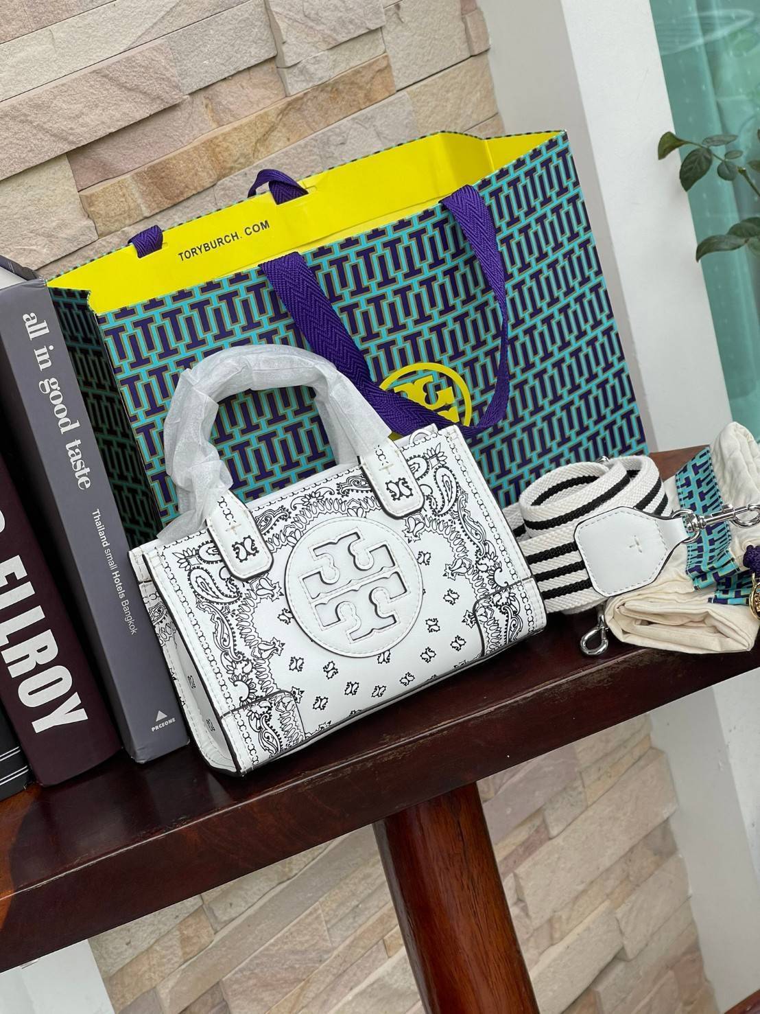Tory Burch Ella Printed Leather Micro Tote Bag กระเป๋าขนาดมินิใบนี้บอกเลยว่าสไตล์เก๋และแปลกตาเลยทีเดียว กระเป๋าทรงสี่เหลี่ยมขนาดมินิ มีสายสะพายที่ออกแบบมาเข้ากับกระเป๋าสำหรับสะพายข้าง ลวดลายและสีสันบนกระเป๋ามีเอกลักษณ์ที่แสดงถึงความเป็นศิลปะแบบทอรี่โดยเฉพ