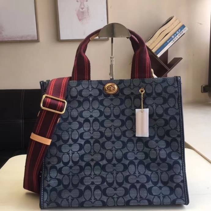COACH Tote 34 In Signature Chambray หากคุณกำลังมองหากระเป๋าที่มีดีไซน์แปลกตา ไม่ค่อยเหมือนที่พบเห็นทั่วไป ต้องเป็นรุ่นนี้เลยค่ะ นอกจากจะผลิตจากผ้าแชมเบรย์ซึ่งมีน้ำหนักเบาแล้ว ยังให้สีสันคล้ายกับสียีนส์ สายสะพายและหูหิ้วสไตล์สปอร์ต ที่สำคัญยังมีหมุดปิดกระเ