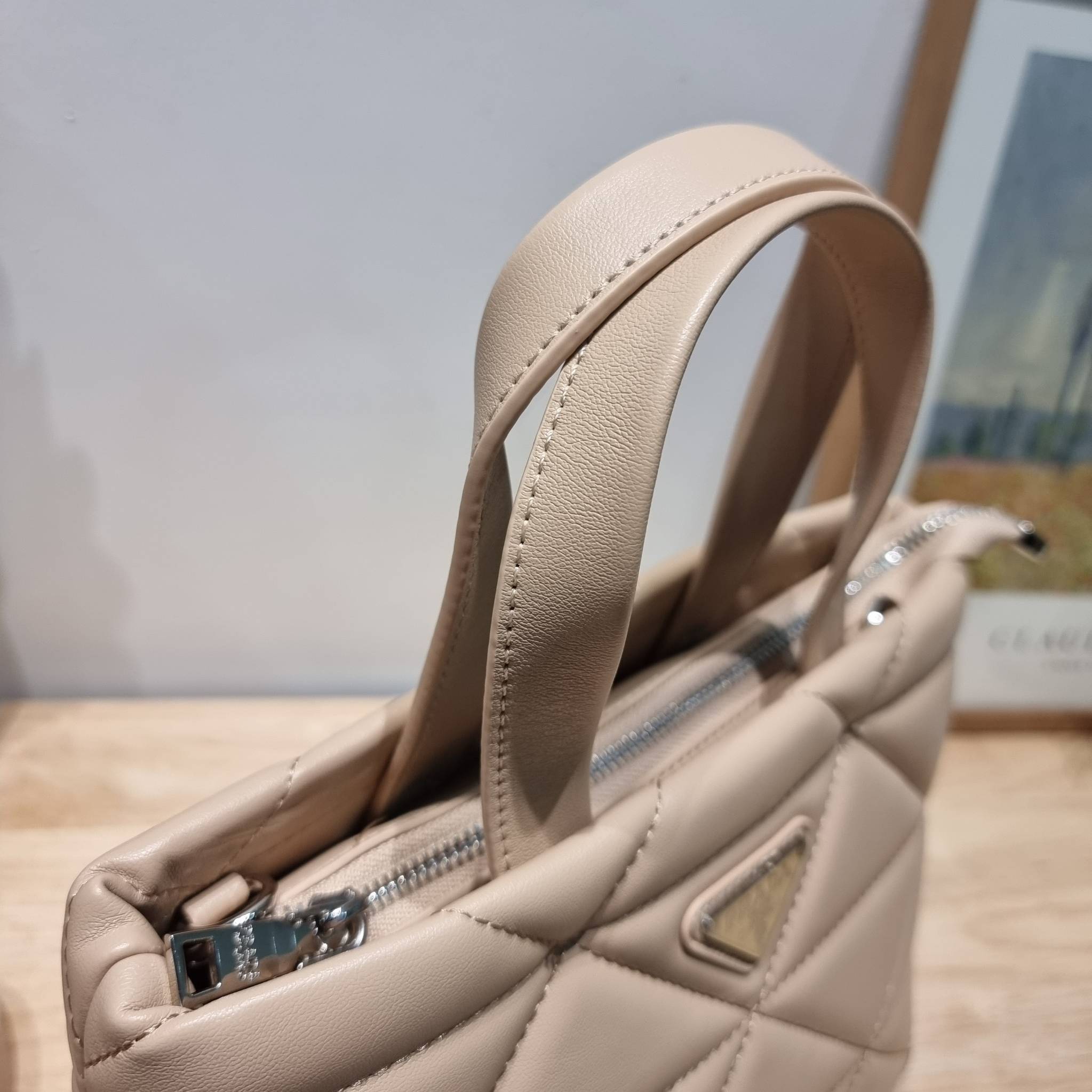 PRADA LEATHER PADDED BAG ใหม่ล่าสุด กับคอลเลคชั่นที่ทำออกมาตอบโจทย์ได้ทุกไลฟ์สไตล์ และเป็นยูนิเซ็กส์ กับกระเป๋าทรงโท้ท ขนาดกำลังดี วัสดุหนังเรียบ ตัดเย็บเดินเส้นลายตาราง ปากกระเป๋ามีซิปเปิดปิด ภายในเป็นช่องโล่ง