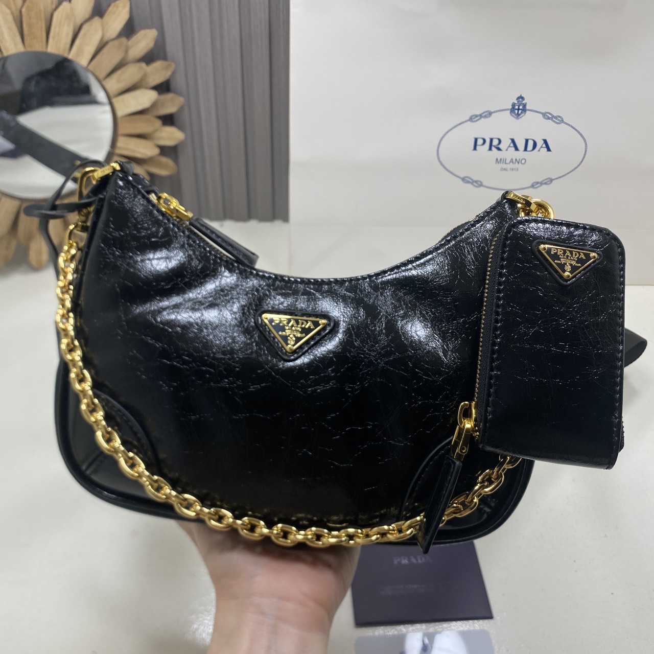 ORI หนังแท้ | Prada Re-Edition 2005 bag in Naplak leather กระเป๋าสะพายทรงโฮโบหนังแก้ว ดีไซน์เอฟเฟกต์มันวาวและเท็กซ์เจอร์ที่มีเสน่ห์สไตล์วินเทจ พร้อมทริกห้อยเพิ่มสไตล์สัมผัสที่โดดเด่นและร่วมสมัยยิ่งขึ้น