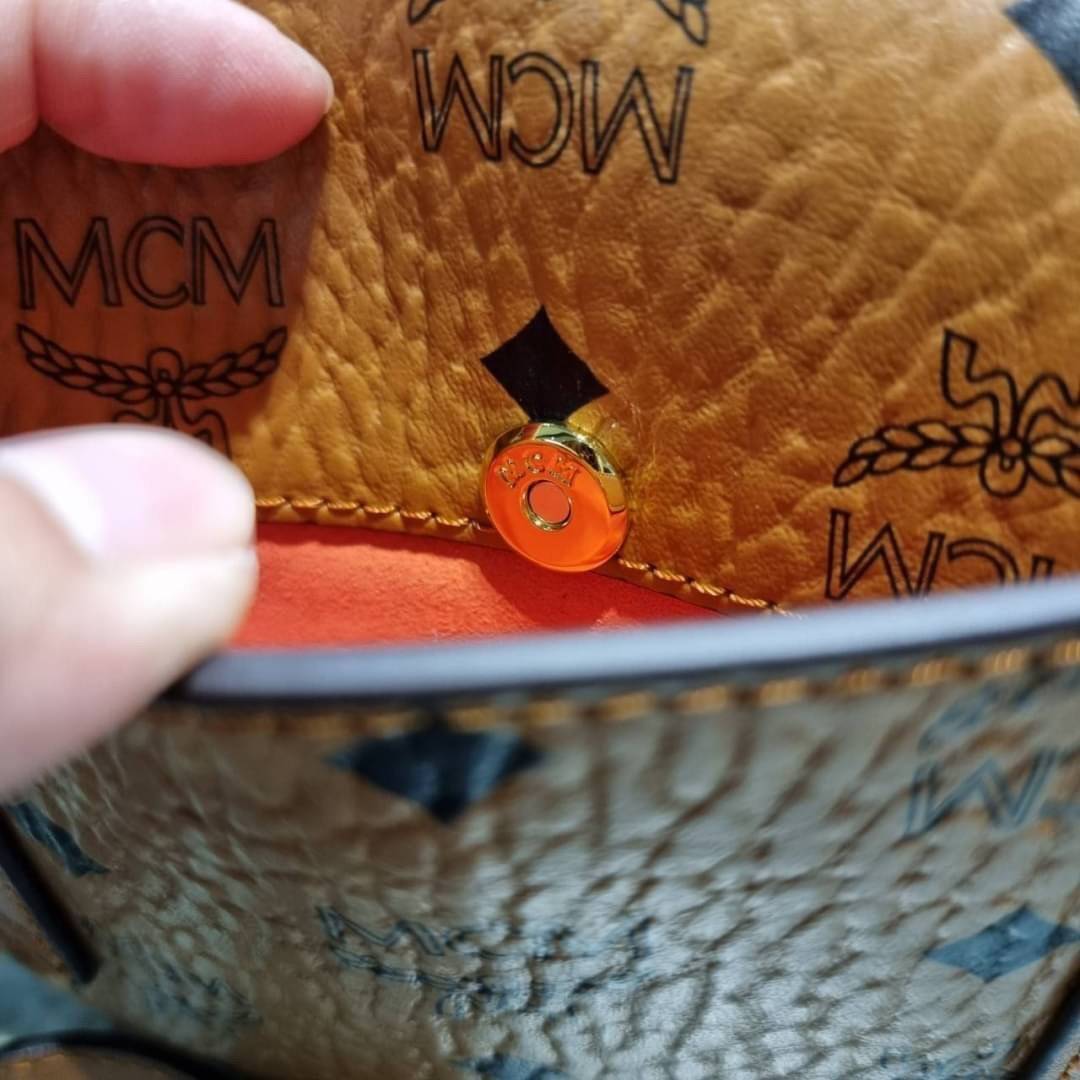 M.C.M MINI PATRICIA CROSSBODY IN VISETOS กระเป๋าสะพายไซส์มินิ แรงดีไม่มีตกน้า คอลเลคชั่นนี้ดีไซน์แปลกใหม่ ทรงโค้งมน สวยหรู ด้านข้างตกแต่งหมุดทองรอบใบ วัสดุตัวกระเป๋าเป็นหนังแคนวาสคุณภาพดี ภายในเป็นหนังกลับสีส้มโดดเด่นเป็นเอกลักษณ์ มีช่องใส่บัตรแยกให้ เปิด