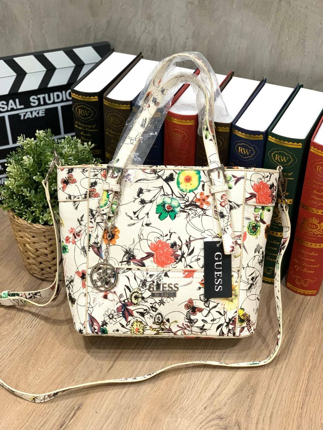 GUESS Women's Medium Floral Tote Bag กระเป๋าถือ คล้องไหล่หรือสะพาย ขนาดกลาง วัสดุหนังpu ลายดอกไม้ชนิดต่างๆรอบใบ เปิดปิดใช้งานด้วยซิปเดียวด้านบน ภายในมีกว้างใส่กระเป๋าสตาวค์ยาว มินิไอแพคได้ หูจับและสายสะพายปรับระดับได้ มาพร้อมกุญแจโลโก้guess สวยน่ารัก