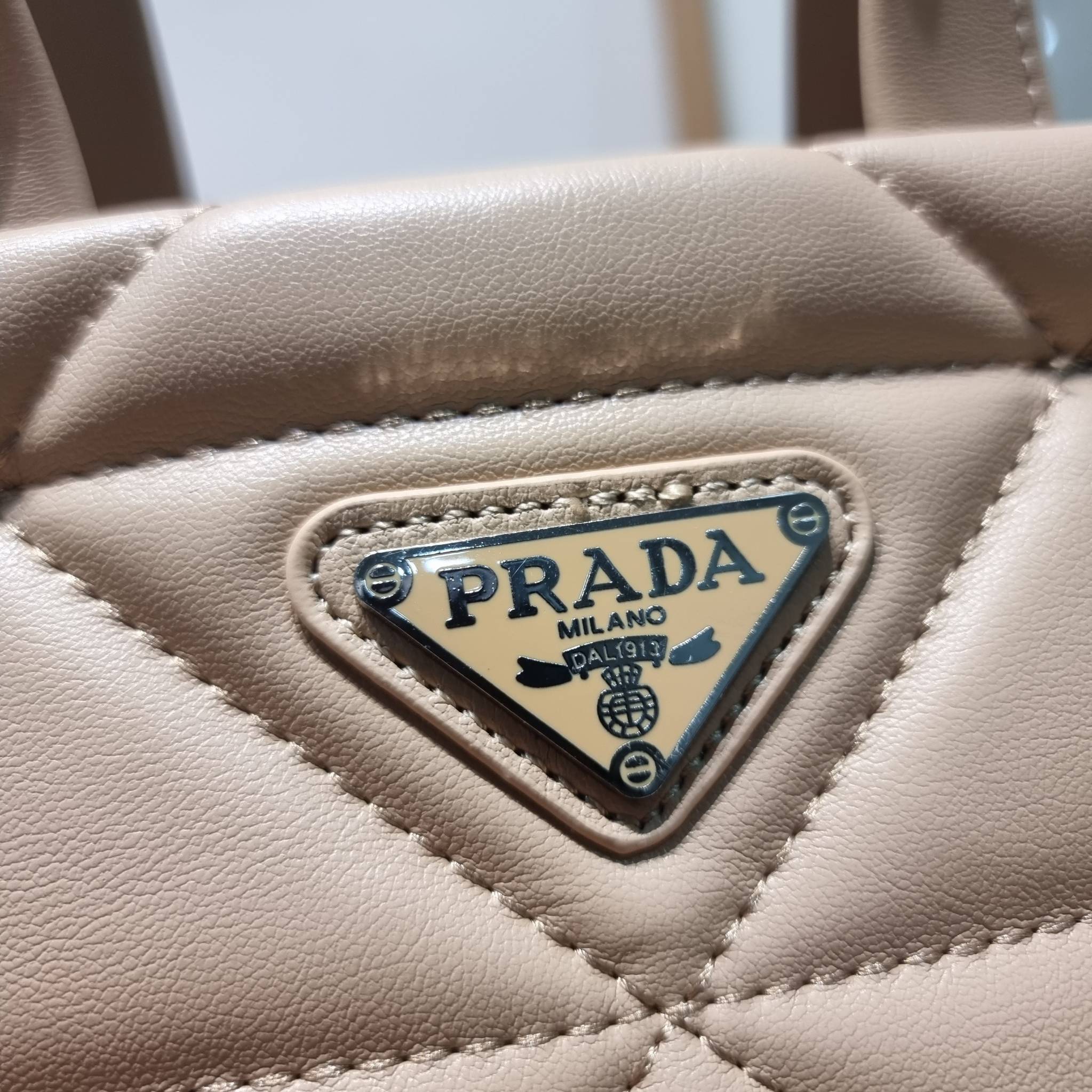 PRADA LEATHER PADDED BAG ใหม่ล่าสุด กับคอลเลคชั่นที่ทำออกมาตอบโจทย์ได้ทุกไลฟ์สไตล์ และเป็นยูนิเซ็กส์ กับกระเป๋าทรงโท้ท ขนาดกำลังดี วัสดุหนังเรียบ ตัดเย็บเดินเส้นลายตาราง ปากกระเป๋ามีซิปเปิดปิด ภายในเป็นช่องโล่ง