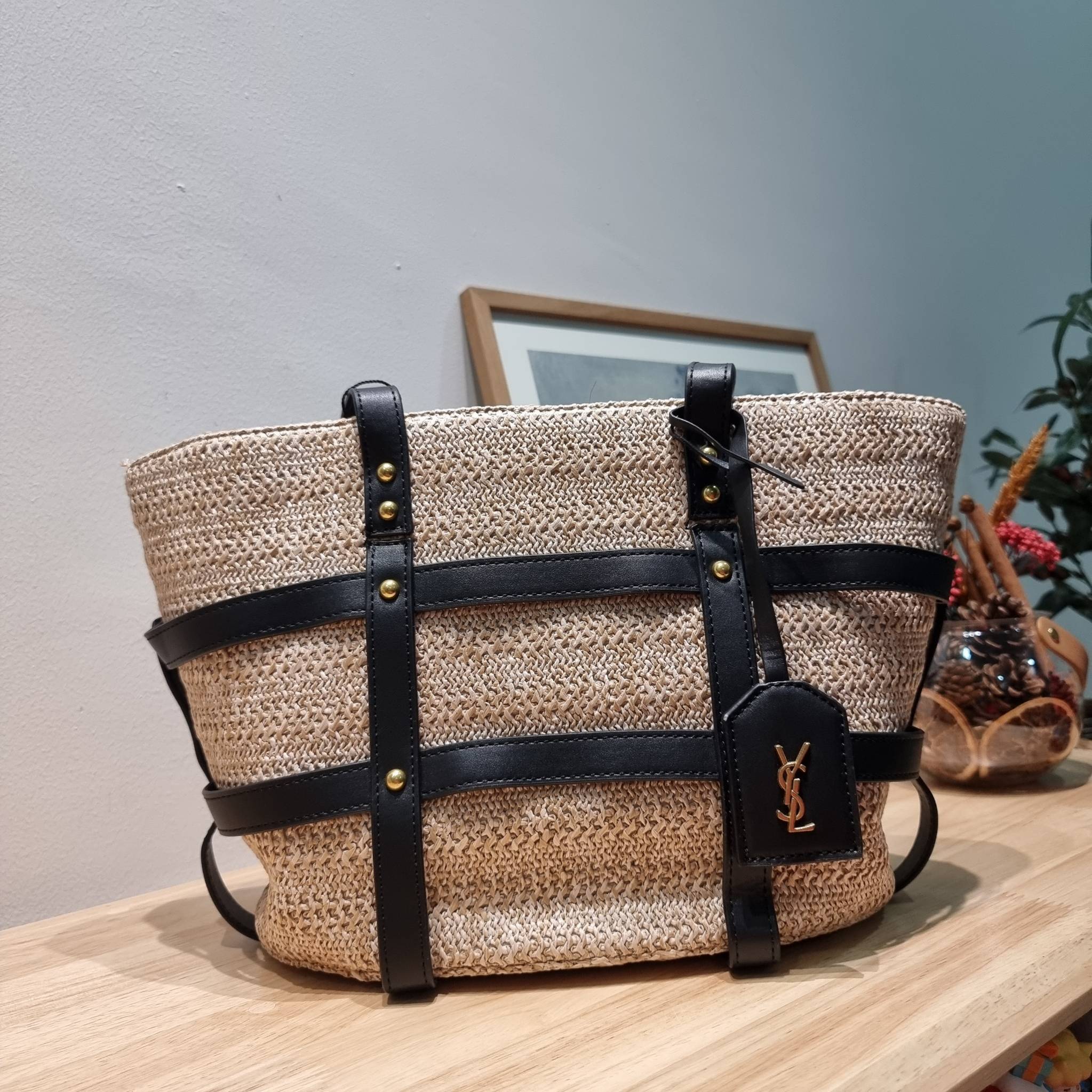 YSL PANIER STUDDED LEATHER TRIMMED WOVEN RAFFIA สวยไม่ซ้ำใคร ใหม่ที่สุด กับกระเป๋าสะพายสานทรงยูนีค ที่เติมดีเทลความหรูด้วยสายหนังคาดตกแต่ง ดูแพงไปอีก