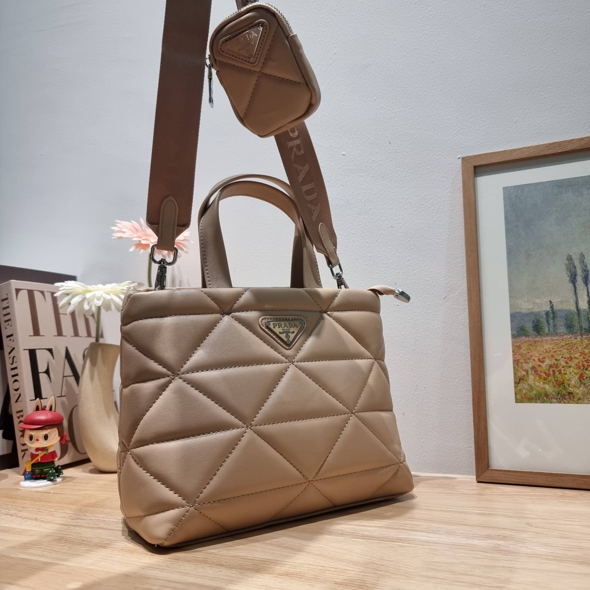 PRADA LEATHER PADDED BAG ใหม่ล่าสุด กับคอลเลคชั่นที่ทำออกมาตอบโจทย์ได้ทุกไลฟ์สไตล์ และเป็นยูนิเซ็กส์ กับกระเป๋าทรงโท้ท ขนาดกำลังดี วัสดุหนังเรียบ ตัดเย็บเดินเส้นลายตาราง ปากกระเป๋ามีซิปเปิดปิด ภายในเป็นช่องโล่ง